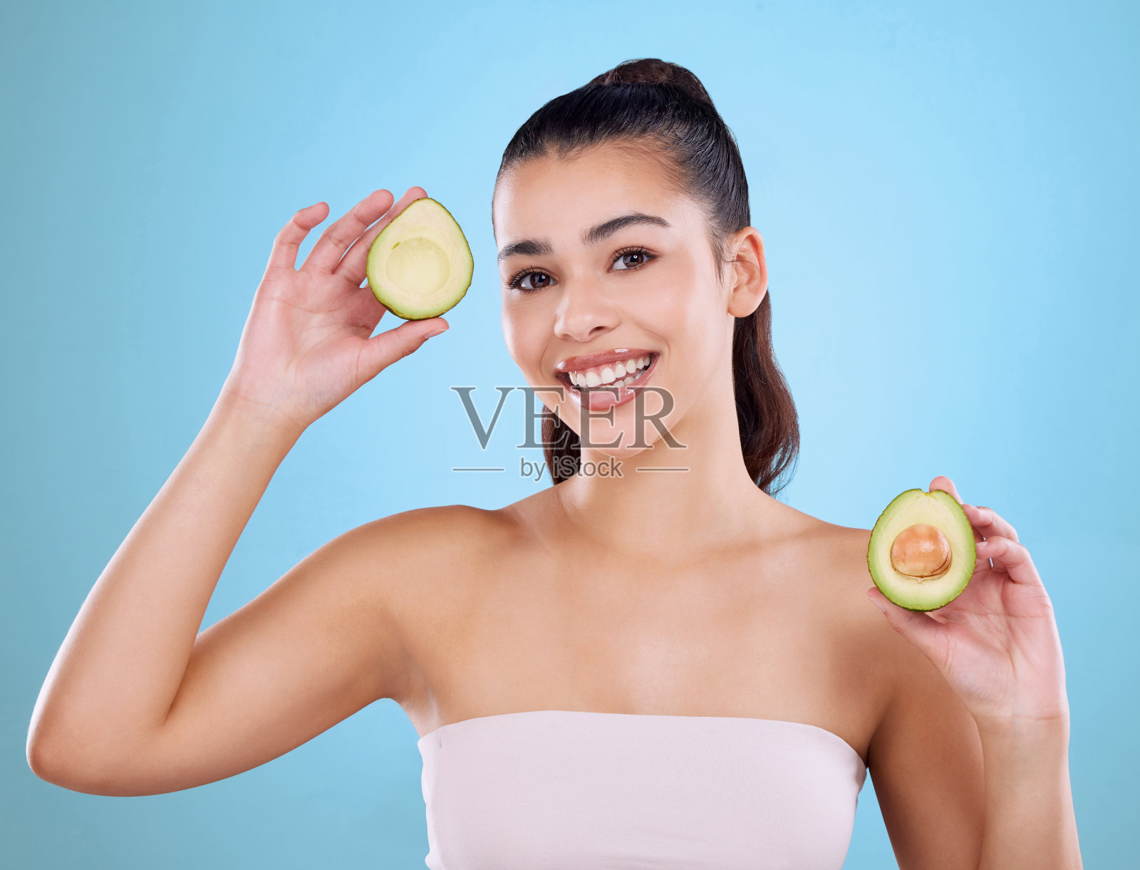 一个有吸引力的年轻女子的工作室肖像摆姿势的两个半avo在蓝色的背景下照片摄影图片