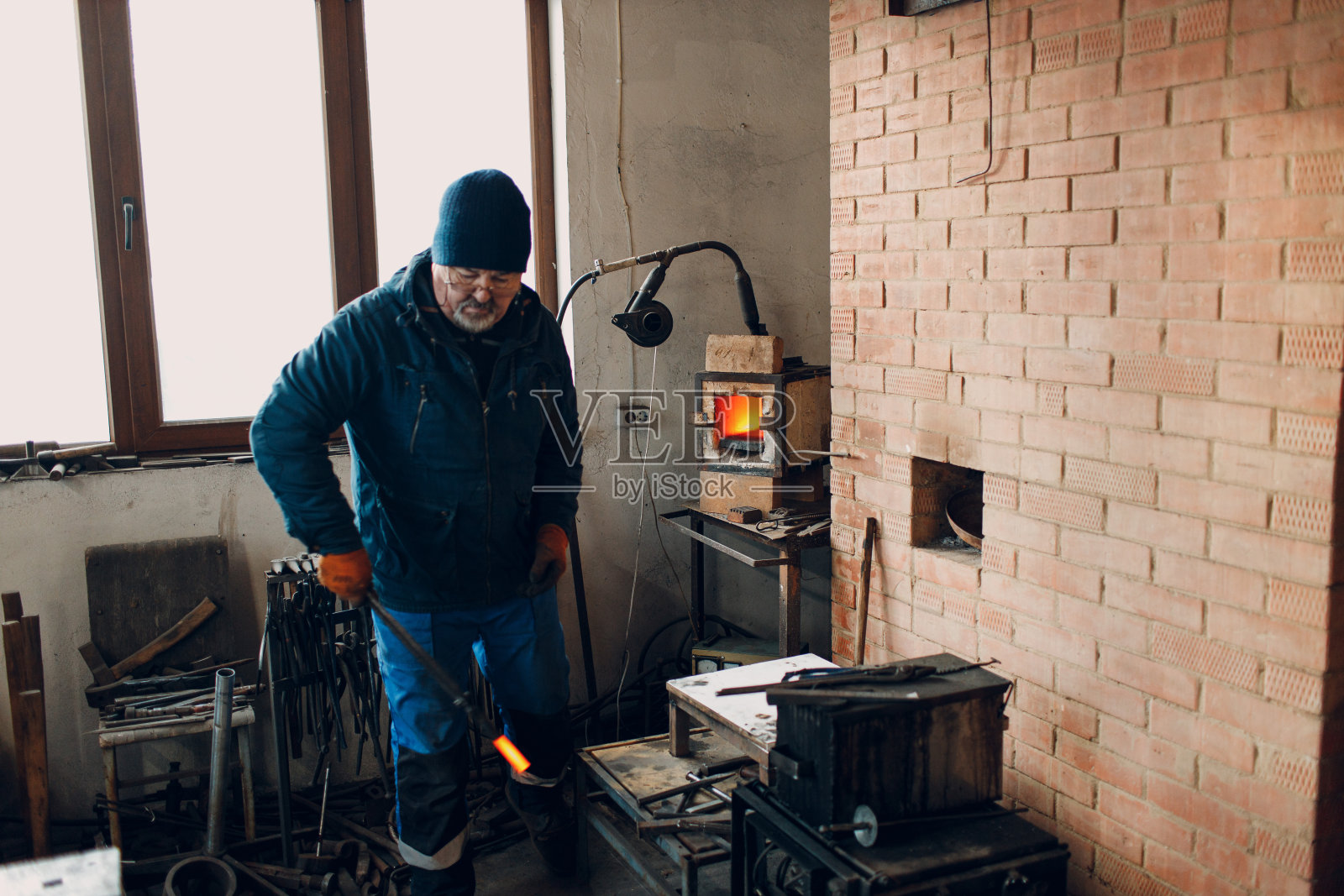 铁匠用炽热的火焰锻造炉子。铁匠在烧得通红的熔炉里加热铁块照片摄影图片