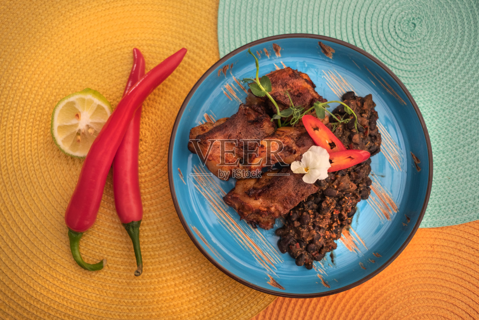 桌上摆着街头墨西哥菜。红烧排骨和豆子。前视图。微绿叶菜、胡椒和青柠。照片摄影图片