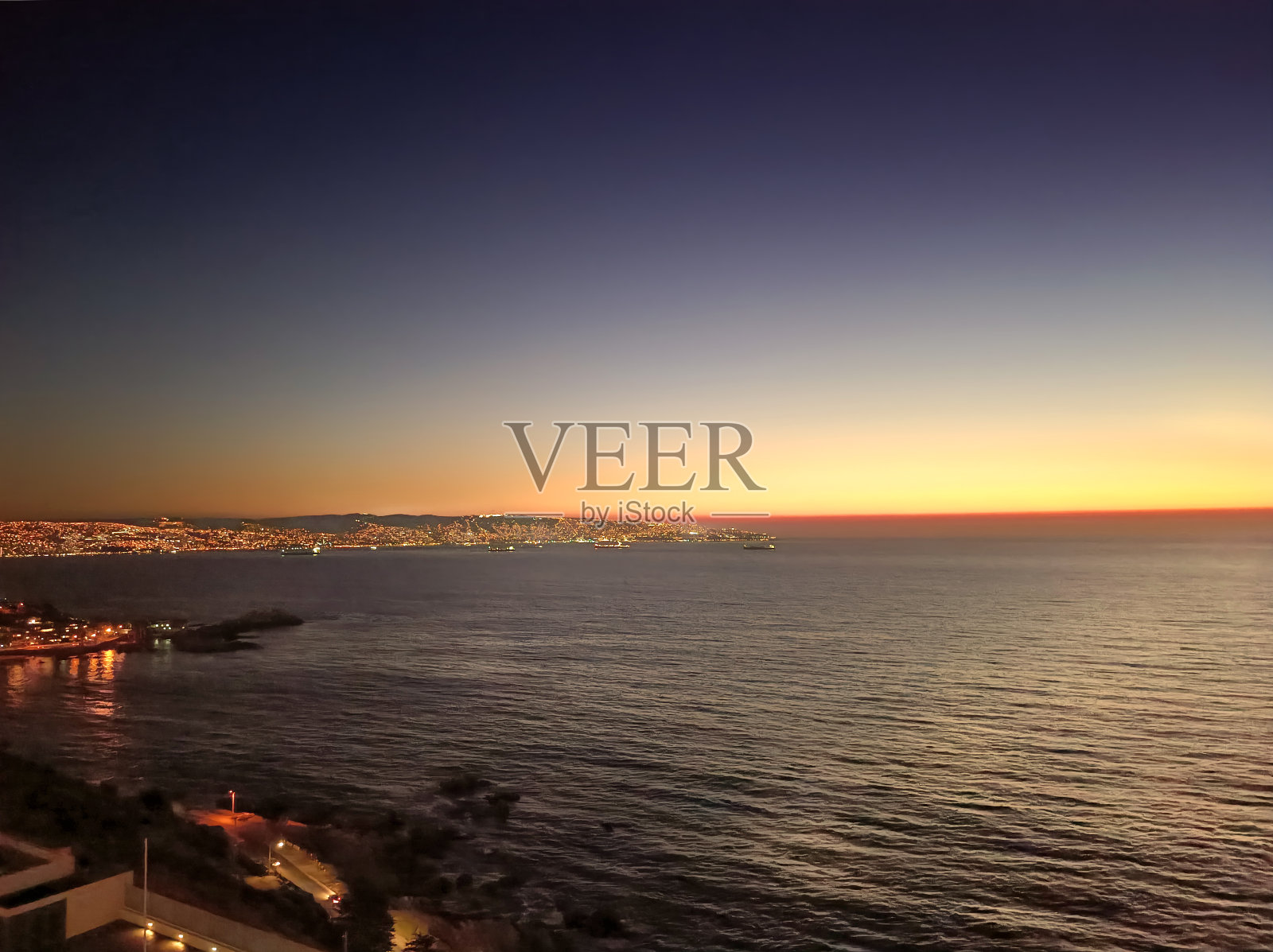 日落时分,位于太平洋沿岸的Viña德尔马市。背景是港口和瓦尔帕莱索市(联合国教科文组织世界遗产)。智利。照片摄影图片