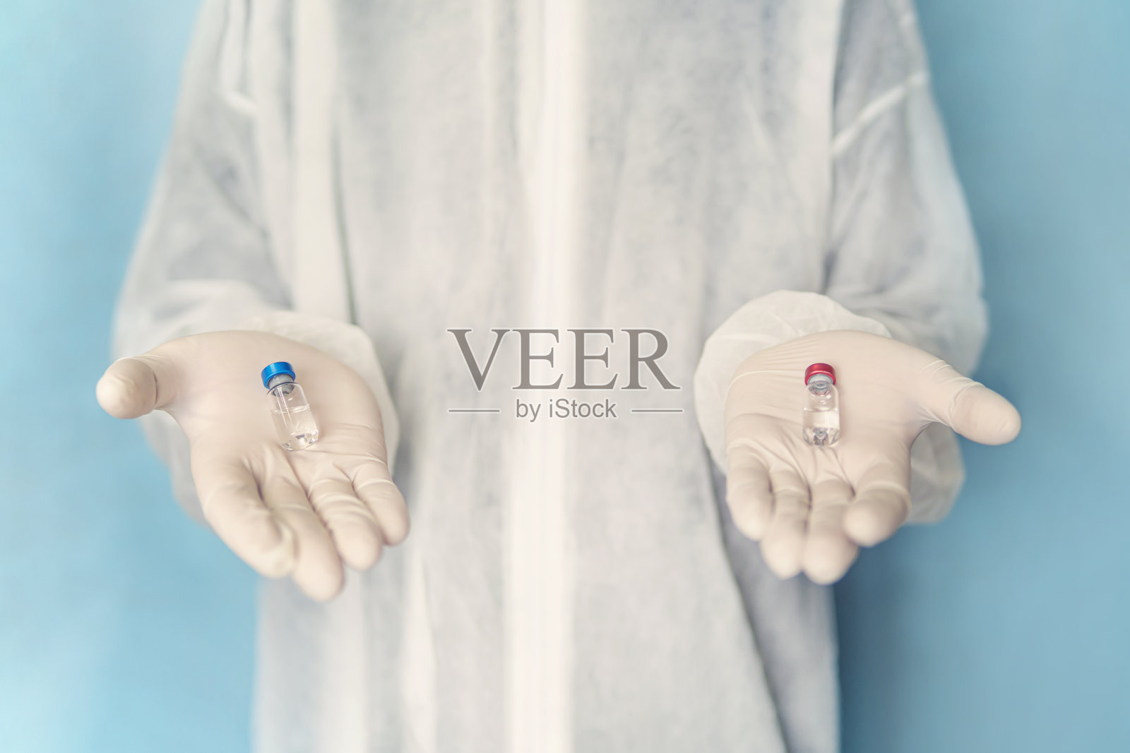 医学概念。药物的选择与母体相似。选择最好的疫苗。医生穿着白大褂,戴着防护手套,手里拿着一个蓝色和红色的安瓿。照片摄影图片