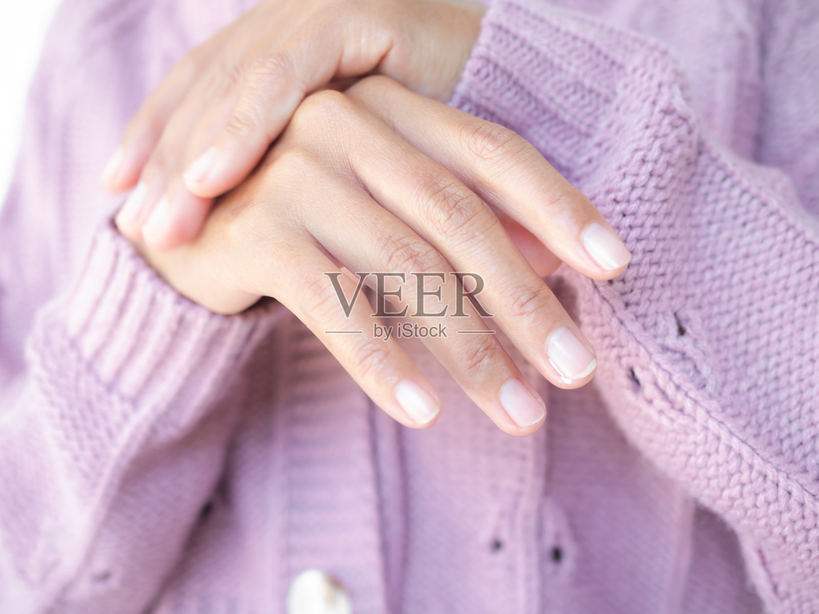 近距离的女人用毛衣涂抹奶油在手上。照片摄影图片