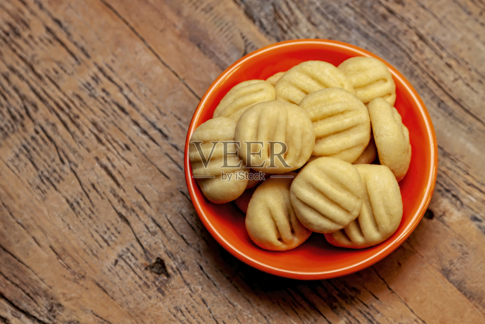 从上面看,自制饼干放在橙色的碗里。照片摄影图片