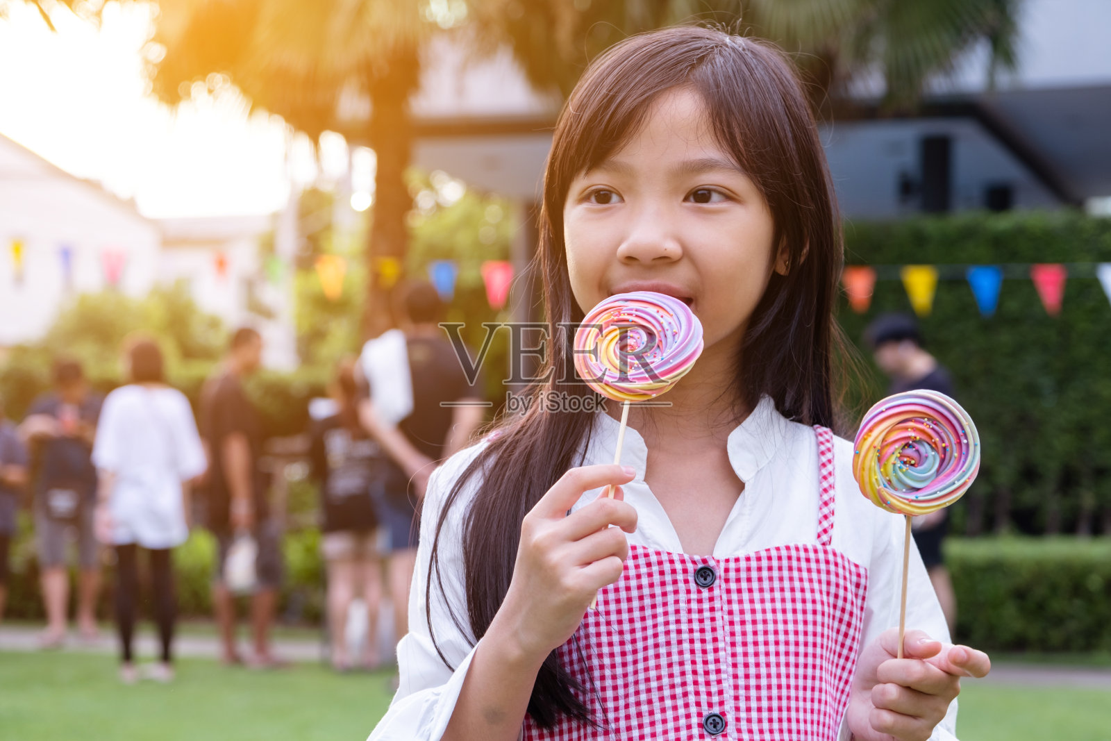 亚洲小女孩高兴地拿着彩虹蛋白糖在她的手中。照片摄影图片