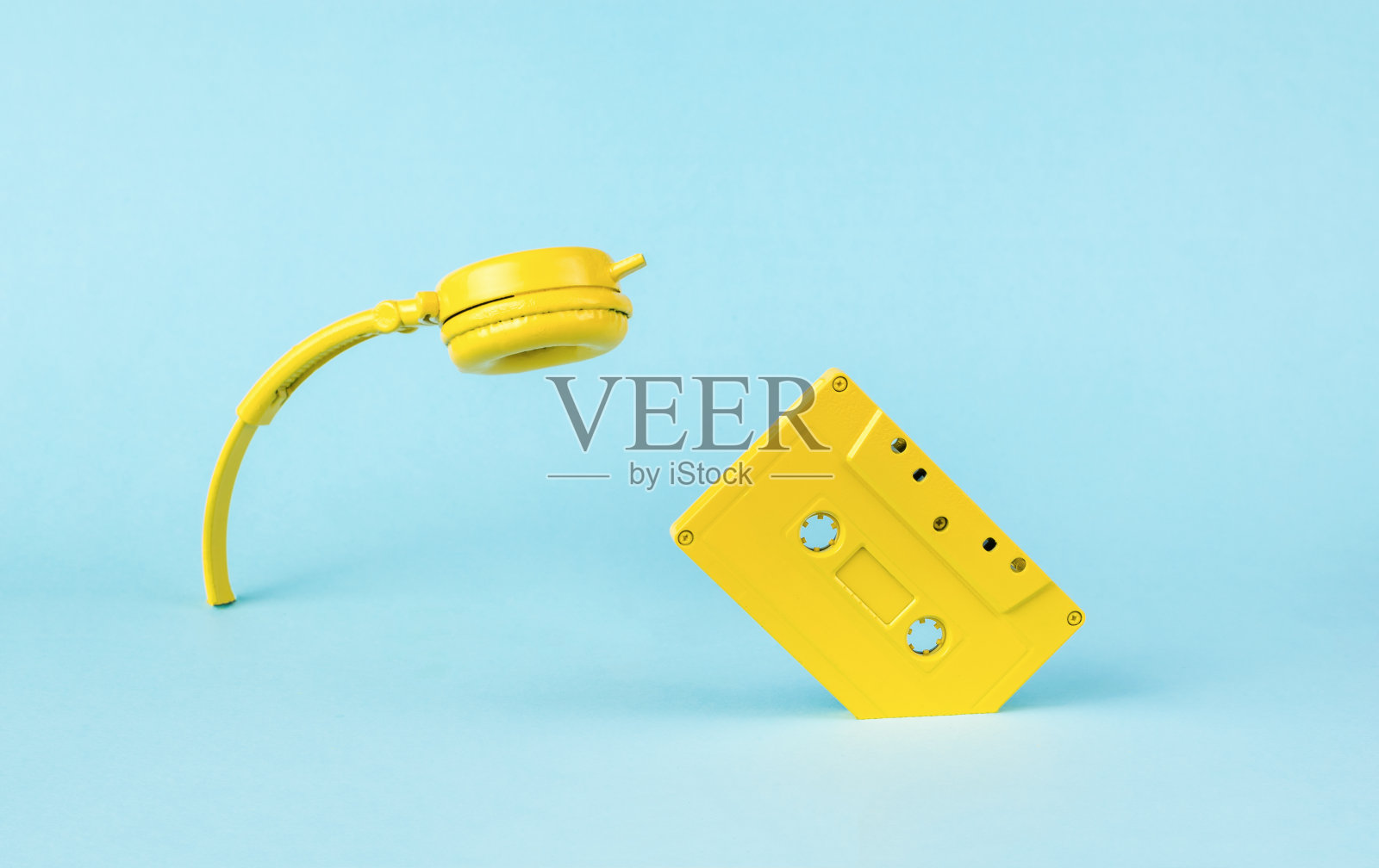 黄色耳机和录音机从蓝色背景中伸出来。老式的录音风格。最小的音频的概念。照片摄影图片