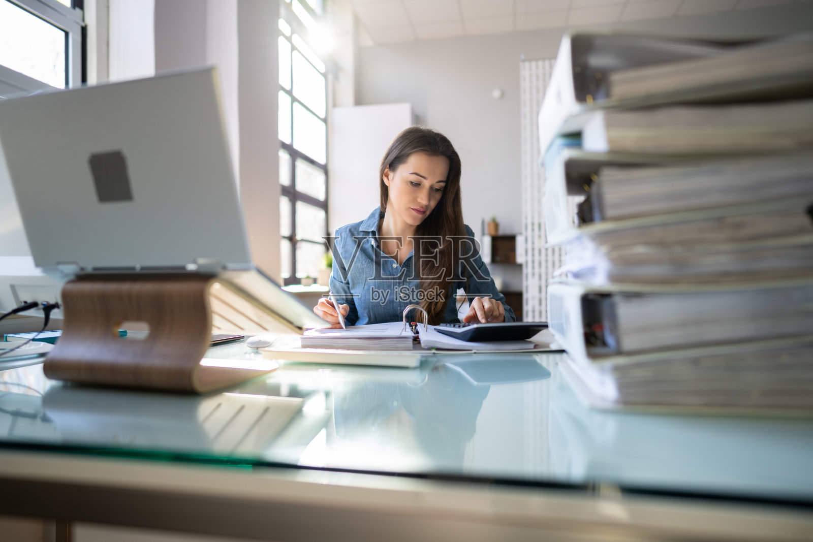 年轻的女商人在办公室工作与成堆的文件夹照片摄影图片