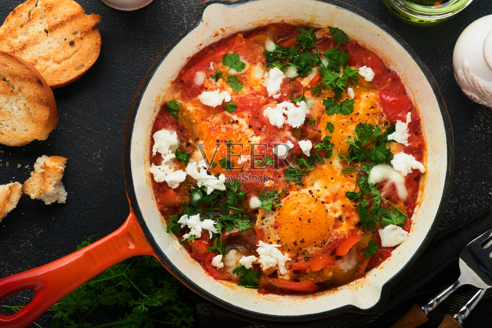 Shakshuka。在旧的深色板岩、石头或混凝土背景上,用铁锅自制的蔬菜煎蛋。以色列的传统菜肴。晚早餐概念。阿拉伯菜。前视图。照片摄影图片