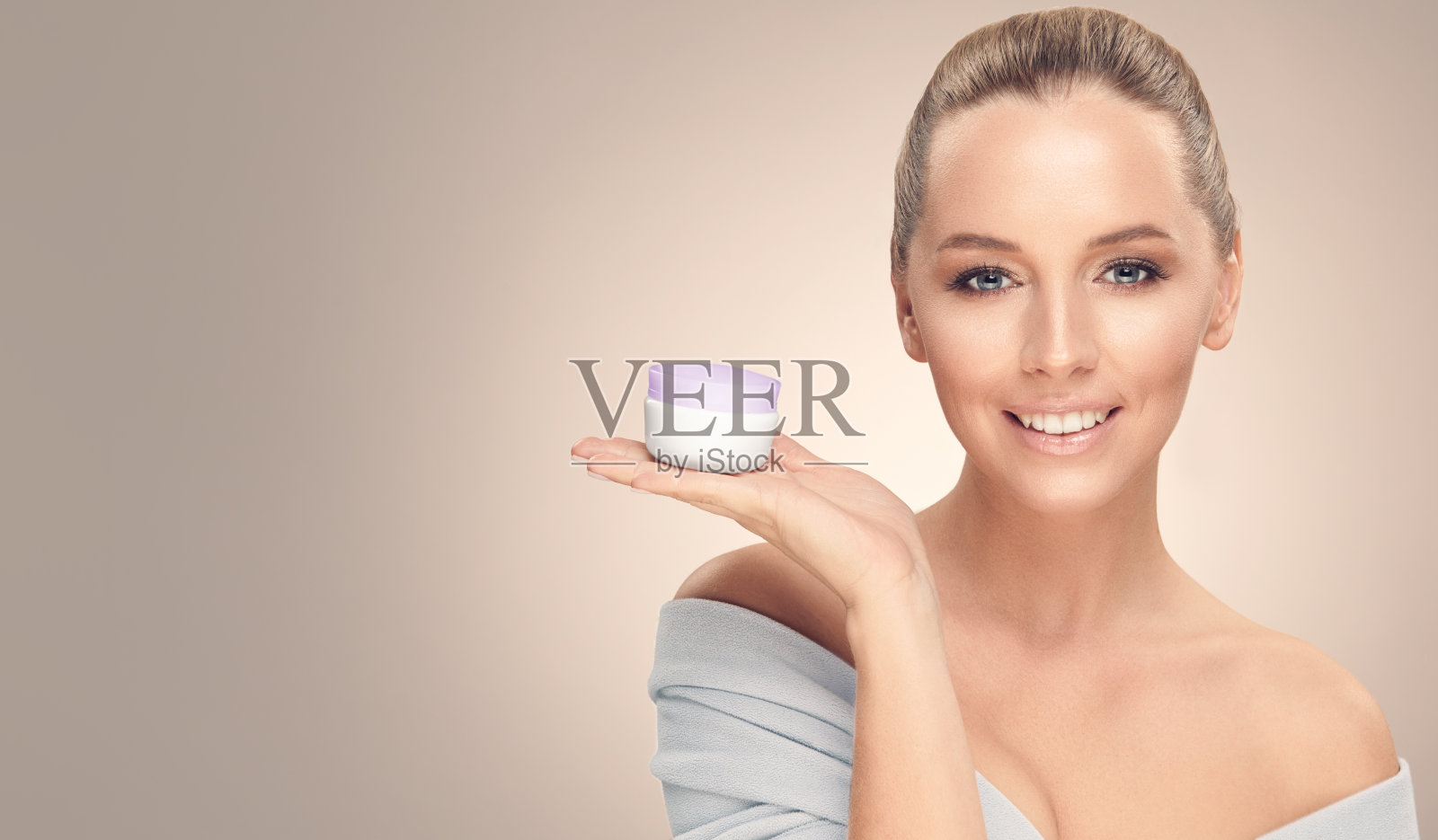 美丽微笑的女模特与干净的皮肤,穿着浴袍在米黄色的抱霜孤立。照片摄影图片