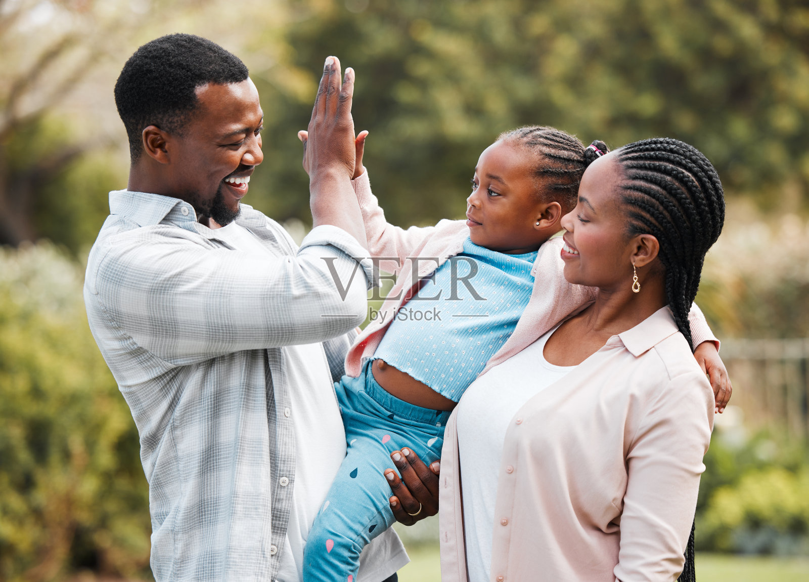 一个年轻的父亲和他的妻子在一起的时候和他的女儿击掌照片摄影图片