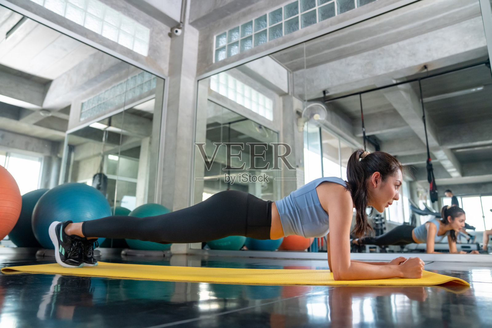 亚洲女运动员穿着运动服在健身房里做平板支撑。照片摄影图片