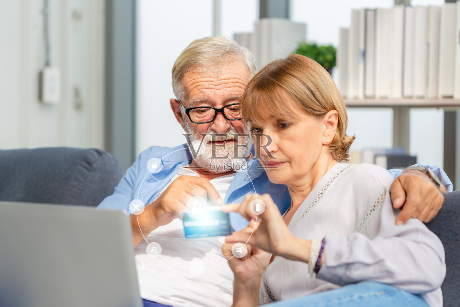 老年夫妇在客厅网上购物,老年男女在舒适的沙发上使用电脑笔记本电脑,幸福的家庭概念照片摄影图片