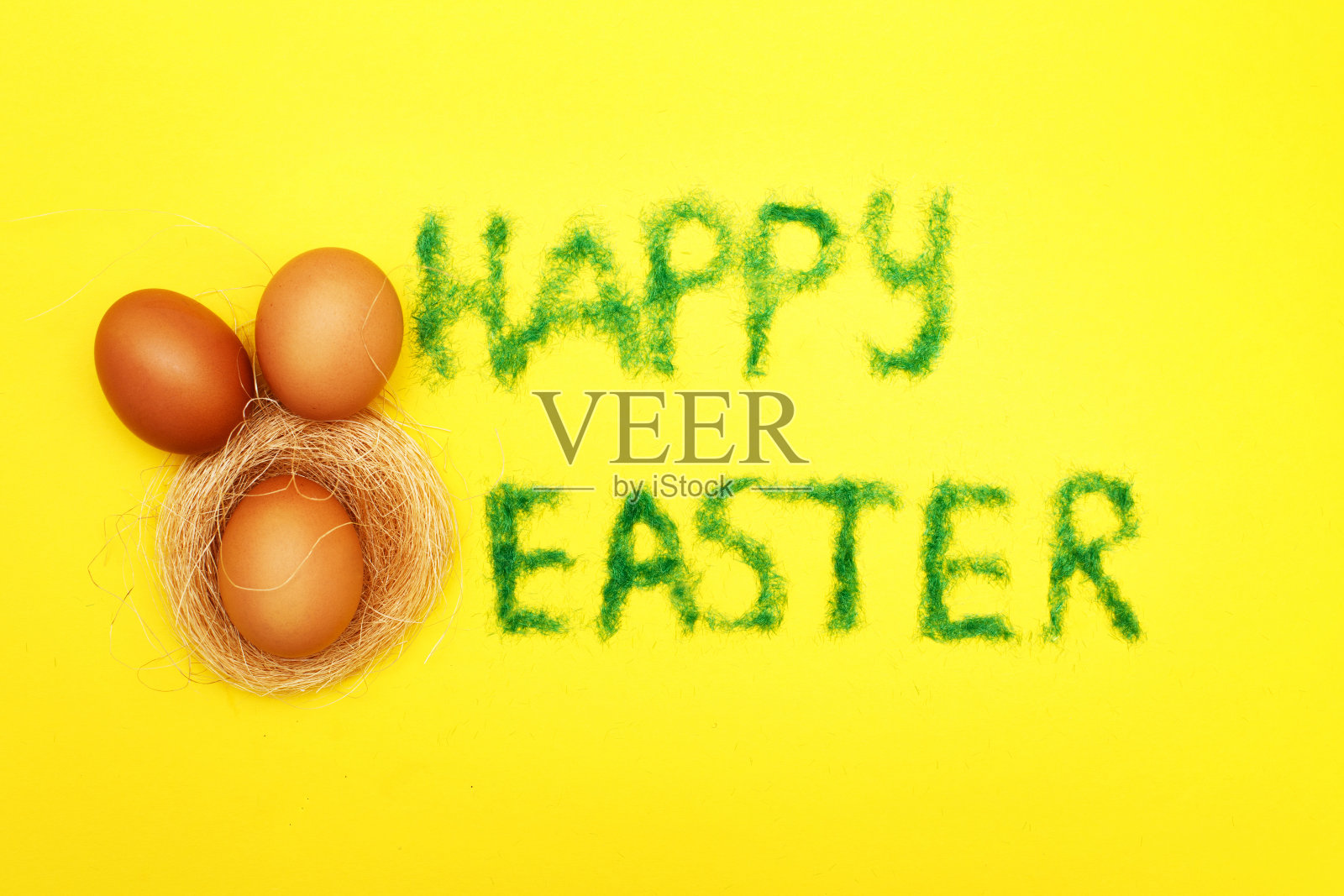题词快乐的复活节从草与兔子蛋和窝在黄色的背景照片摄影图片