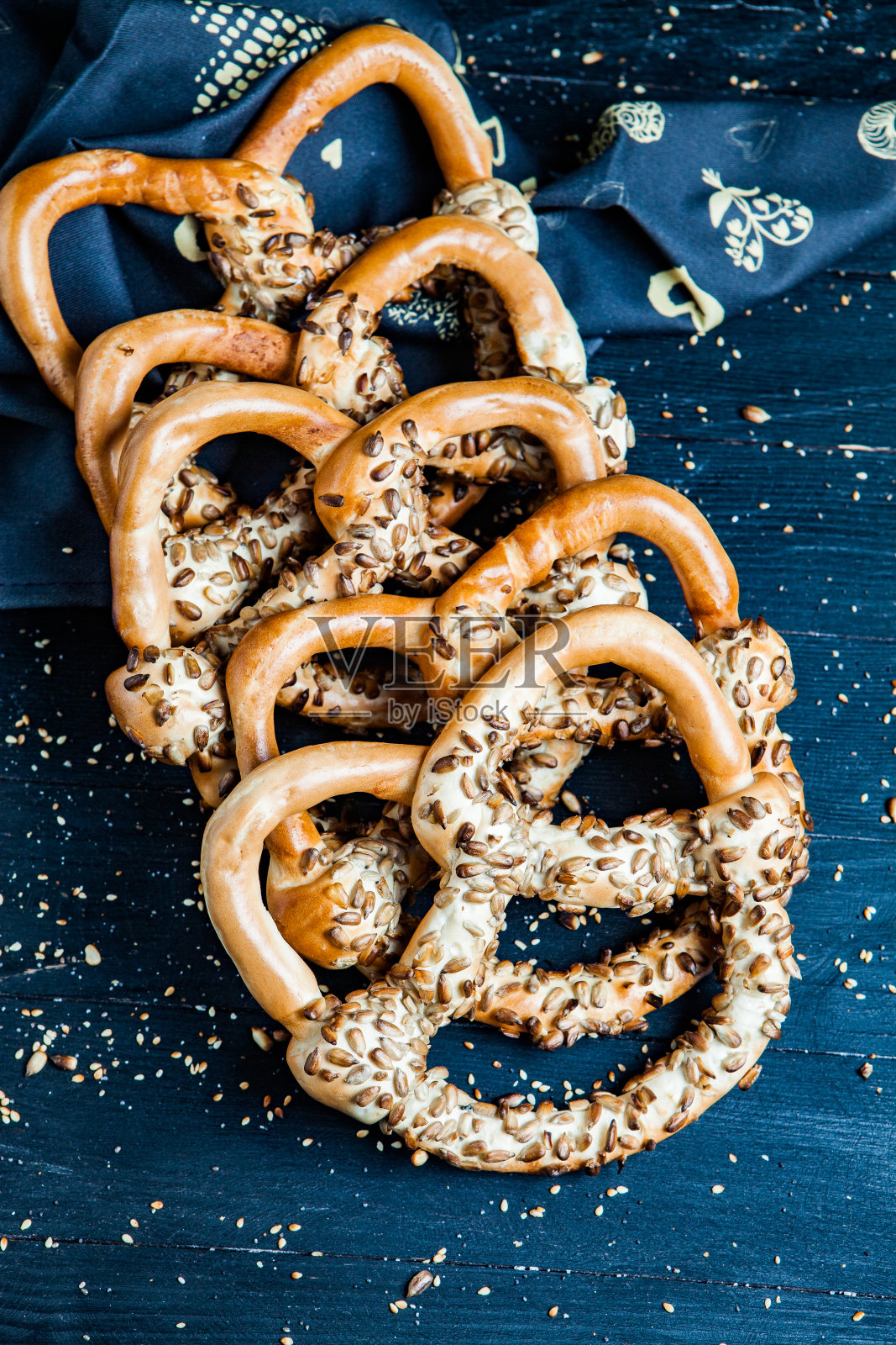 新鲜自制软椒盐卷饼。黑色背景上不同类型的带籽烤百吉饼。照片摄影图片