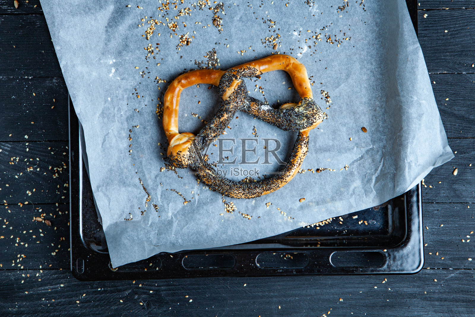 新鲜自制软椒盐卷饼。黑色背景上不同类型的带籽烤百吉饼。照片摄影图片