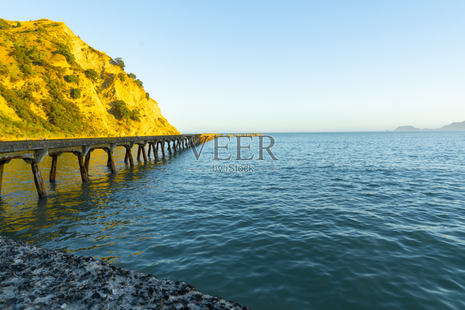 夕阳照亮悬崖和海湾尽头的历史码头照片摄影图片