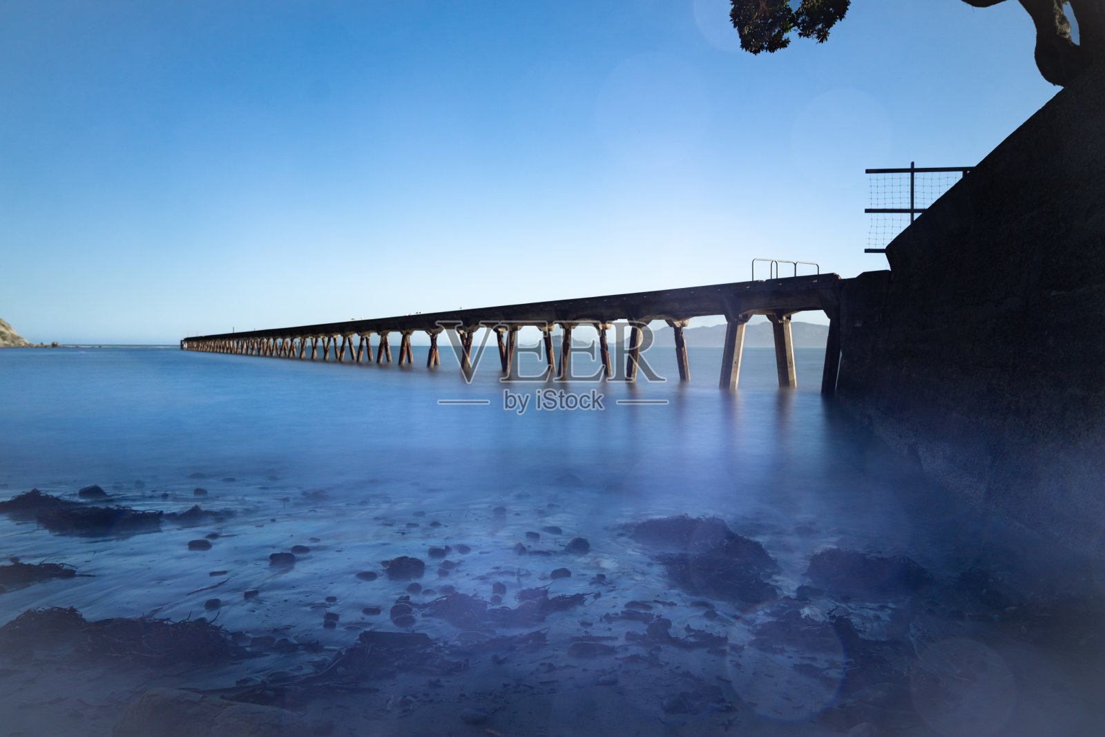 历史悠久的鸟丸湾码头的长曝光图像从低处投射到海湾中照片摄影图片