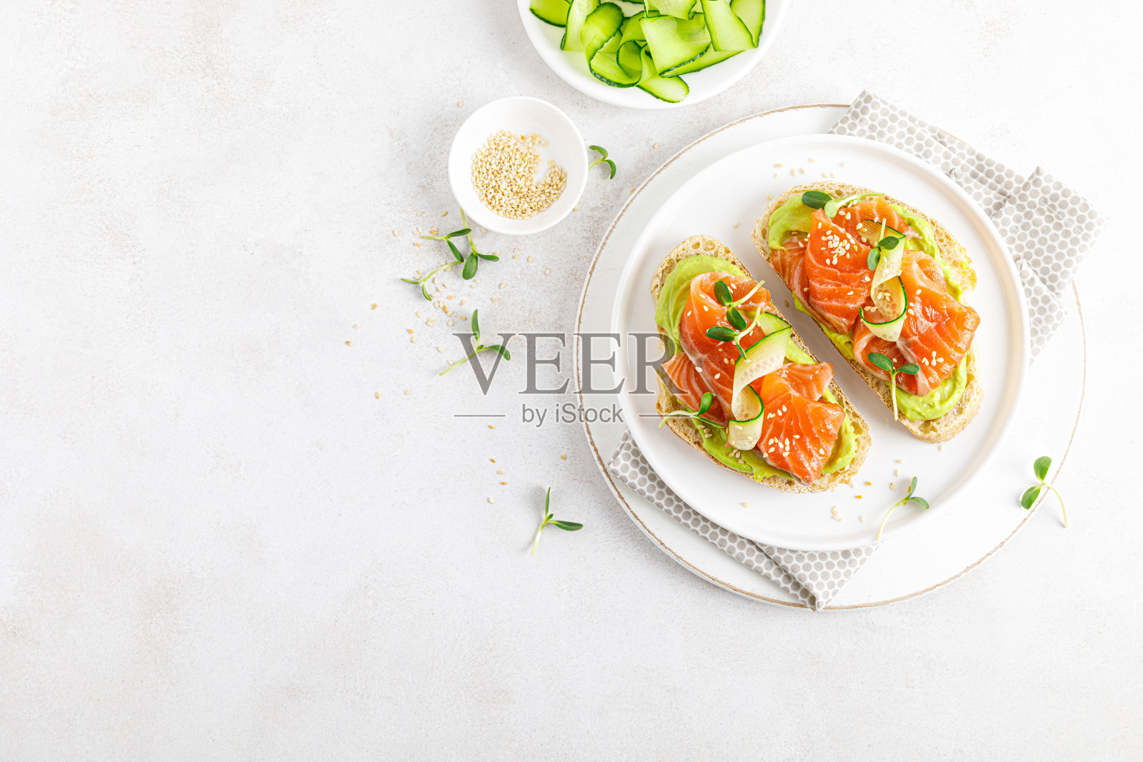用腌鲑鱼、鳄梨色拉酱、牛油果和微绿色蔬菜打开三明治。海鲜。健康食品。前视图。照片摄影图片