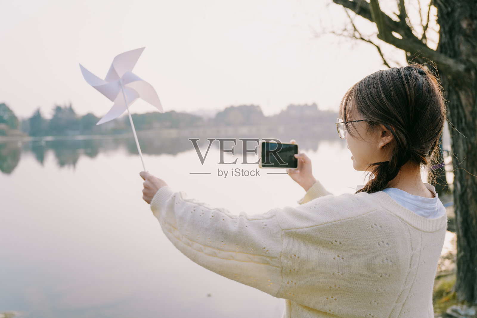 美丽的亚洲女孩拍照与他们的手机附近的湖在黄昏照片摄影图片