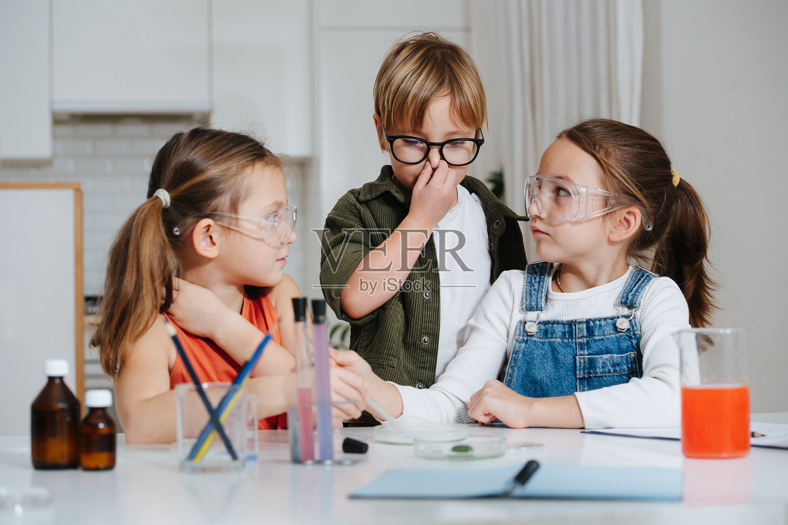 有趣的小孩子在做科学实验,不确定地看着彼此照片摄影图片