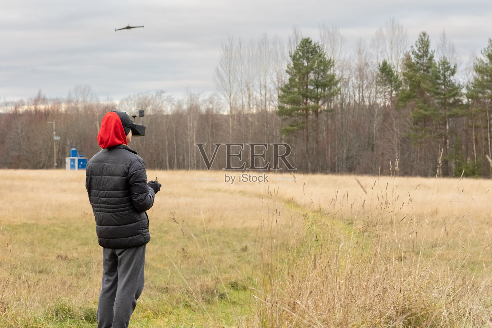 一个年轻人将遥控飞机发射到空中。戴着眼镜的少年在户外玩玩具遥控飞机。男孩拿着无线电遥控器。照片摄影图片