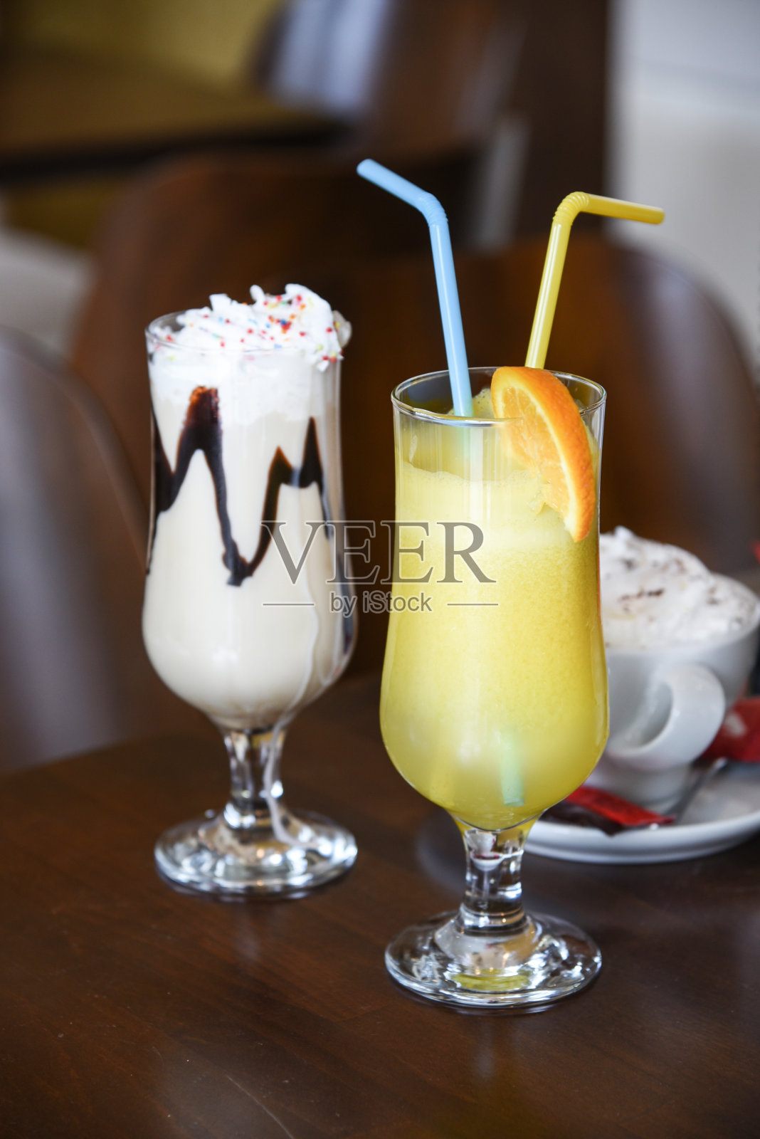 桌上有美味的饮料。杯子里的咖啡加鲜奶油。果汁的吸管。照片摄影图片