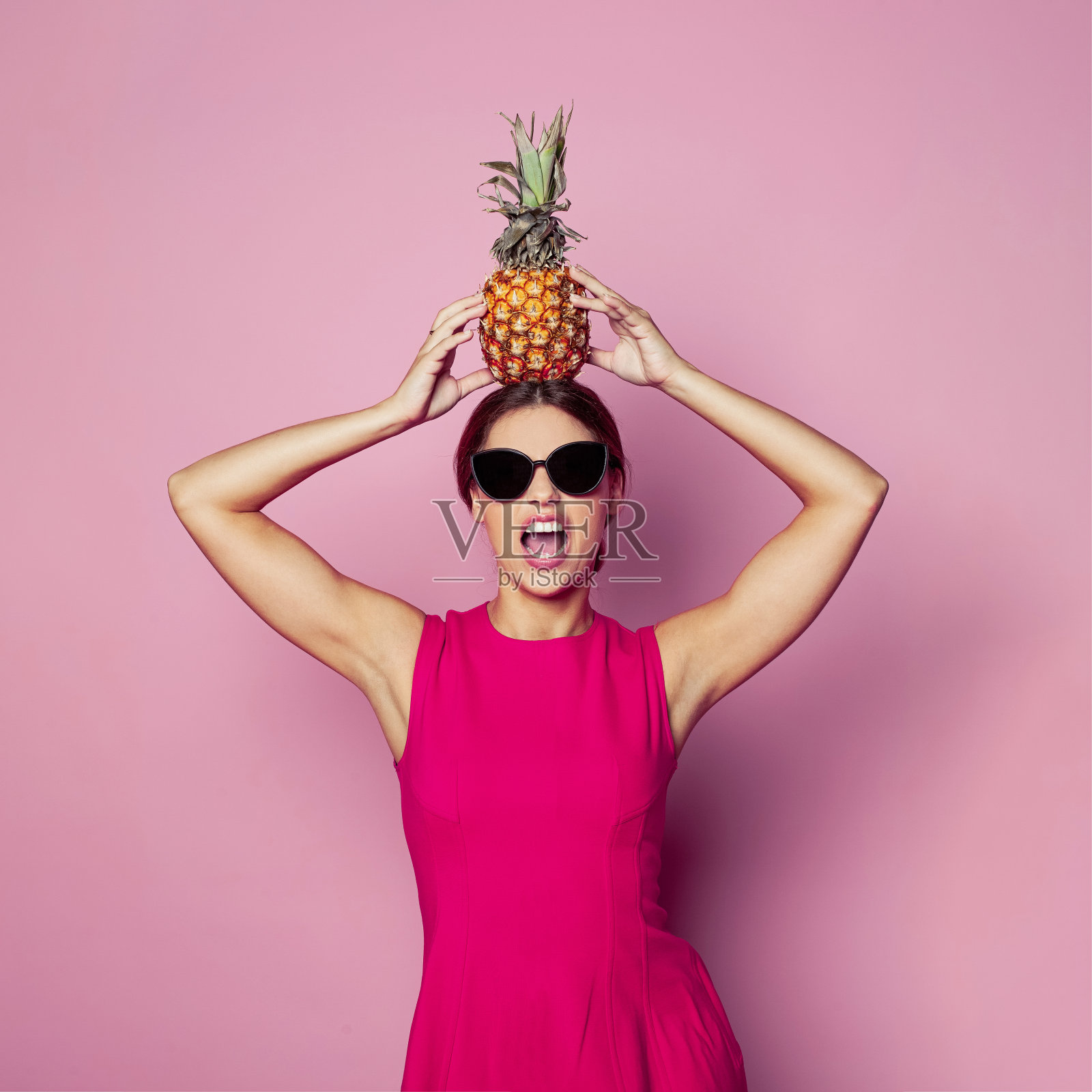 快乐的女人带着菠萝尖叫在粉红色,肖像照片摄影图片