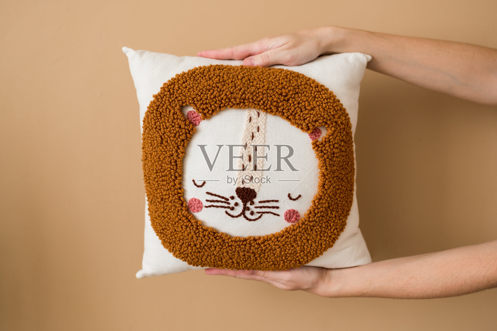 打孔针刺绣枕头diy。女人手抱枕头的特写镜头。产品是用木柄针在基布上按图案推毛线而成照片摄影图片