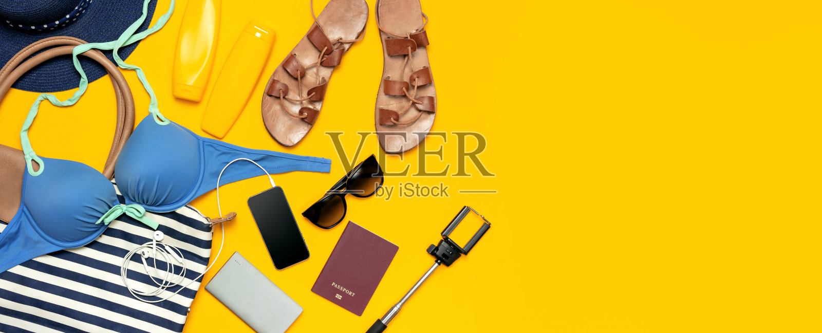 女性夏季服装配饰黄色的背景。旅游度假海的概念。帽子泳装牛仔短裤皮革凉鞋太阳镜防晒海包护照手机。平铺俯视图照片摄影图片