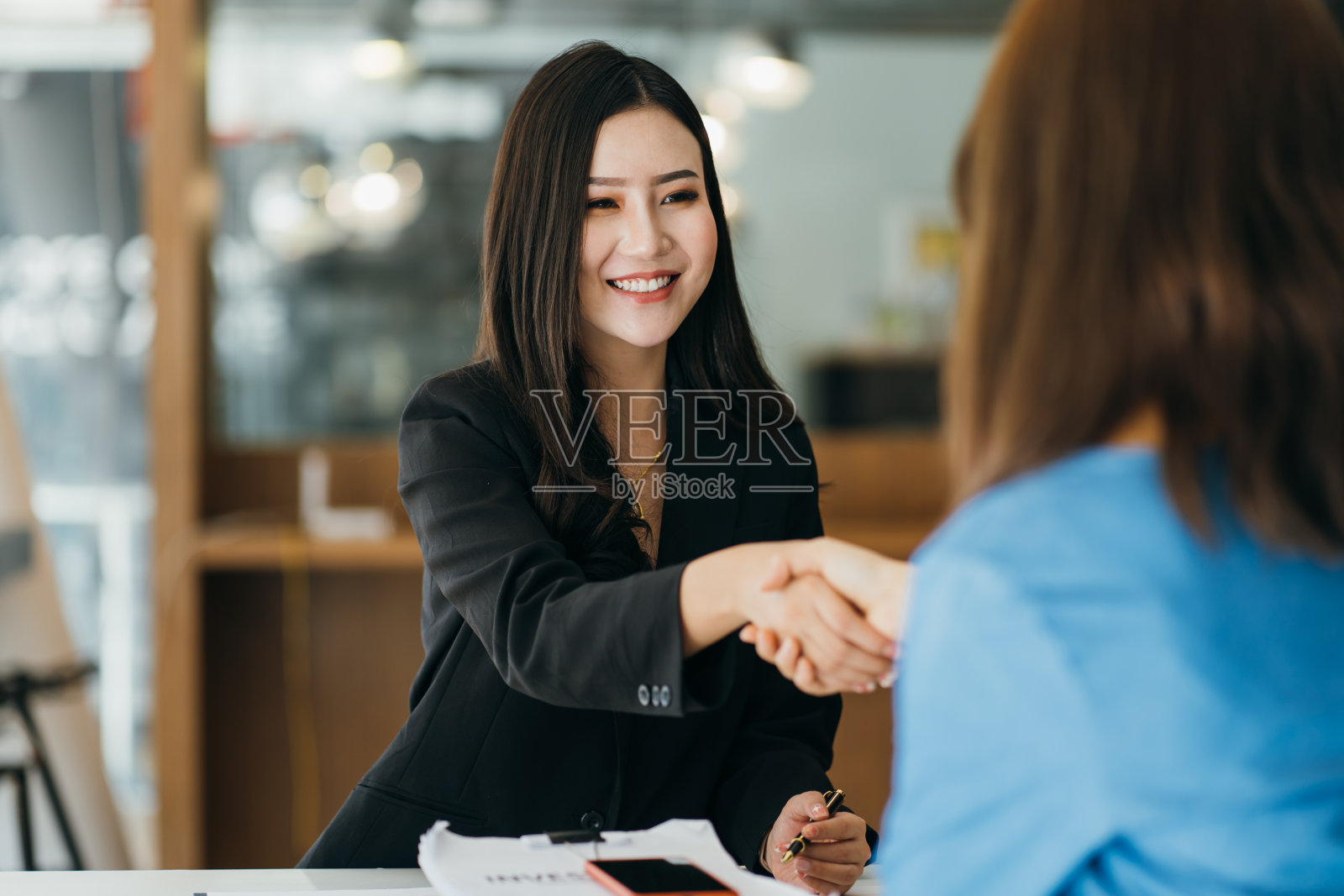 两个女商人在现代办公室里握手照片摄影图片