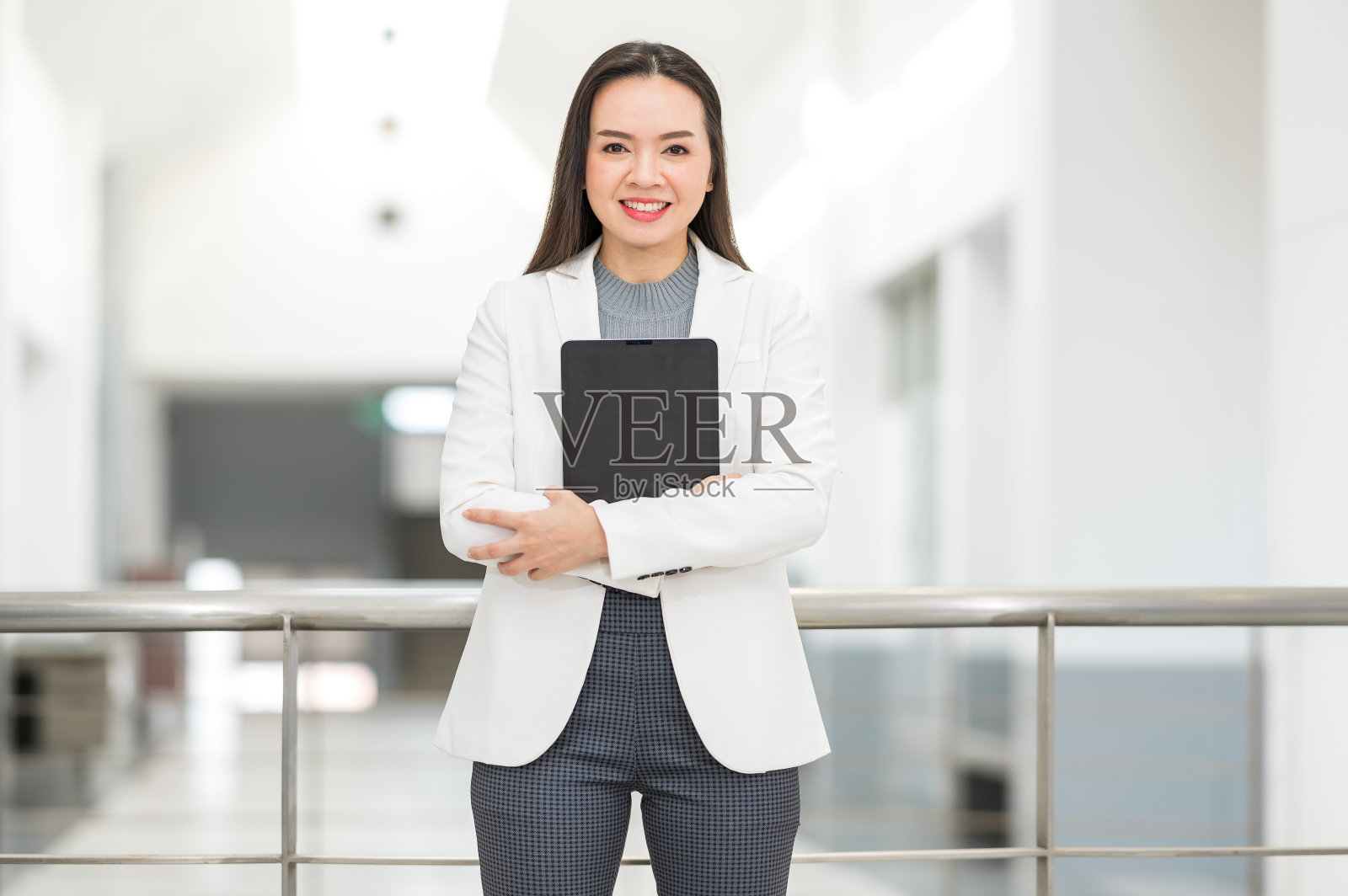 一幅成功的亚洲女商人的肖像,穿着轻松的商务套装,在商业大楼之间拿着平板电脑照片摄影图片