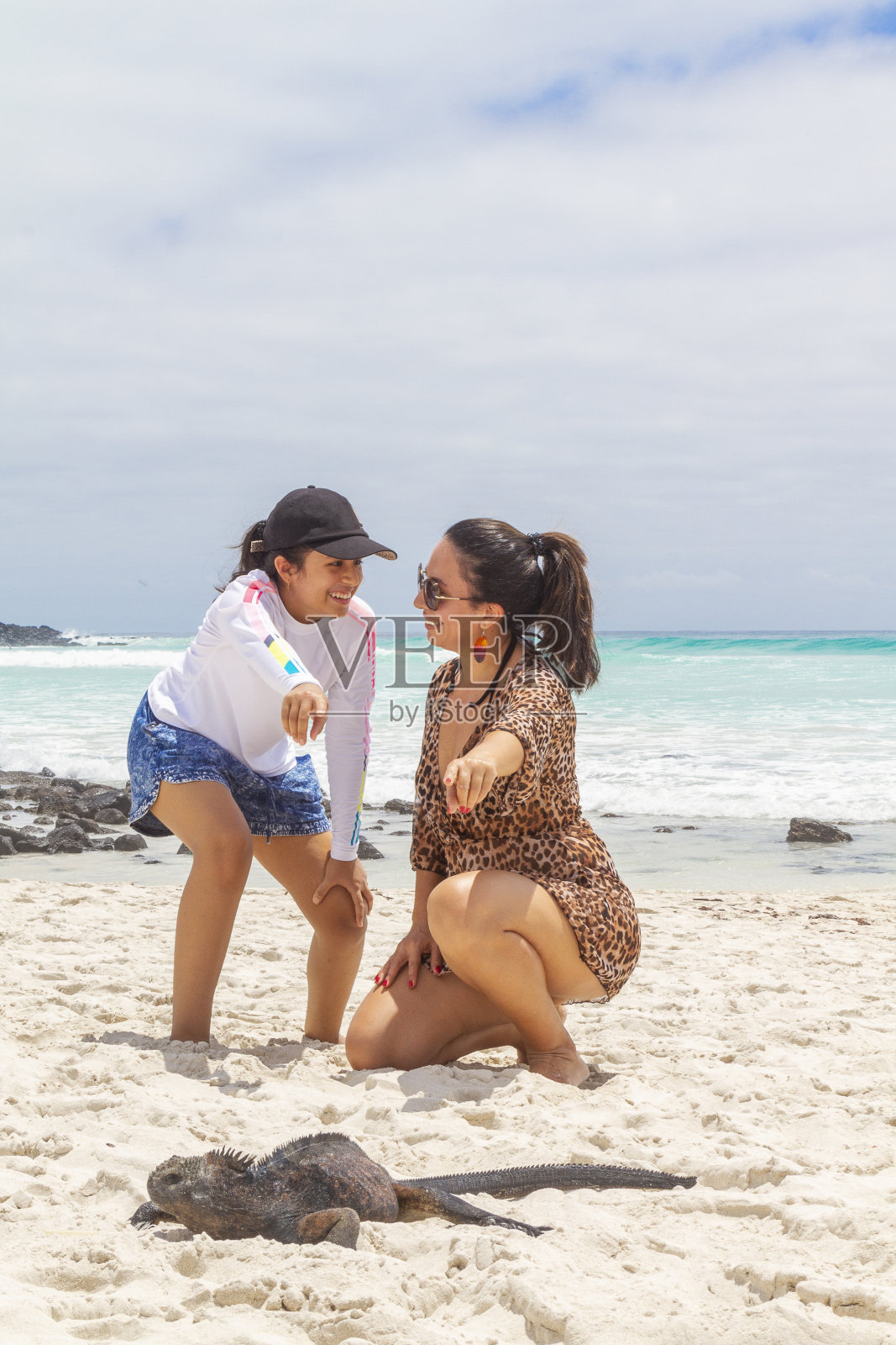 在加拉帕戈斯群岛,厄瓜多尔,欣赏鬣蜥的少女和母亲照片摄影图片