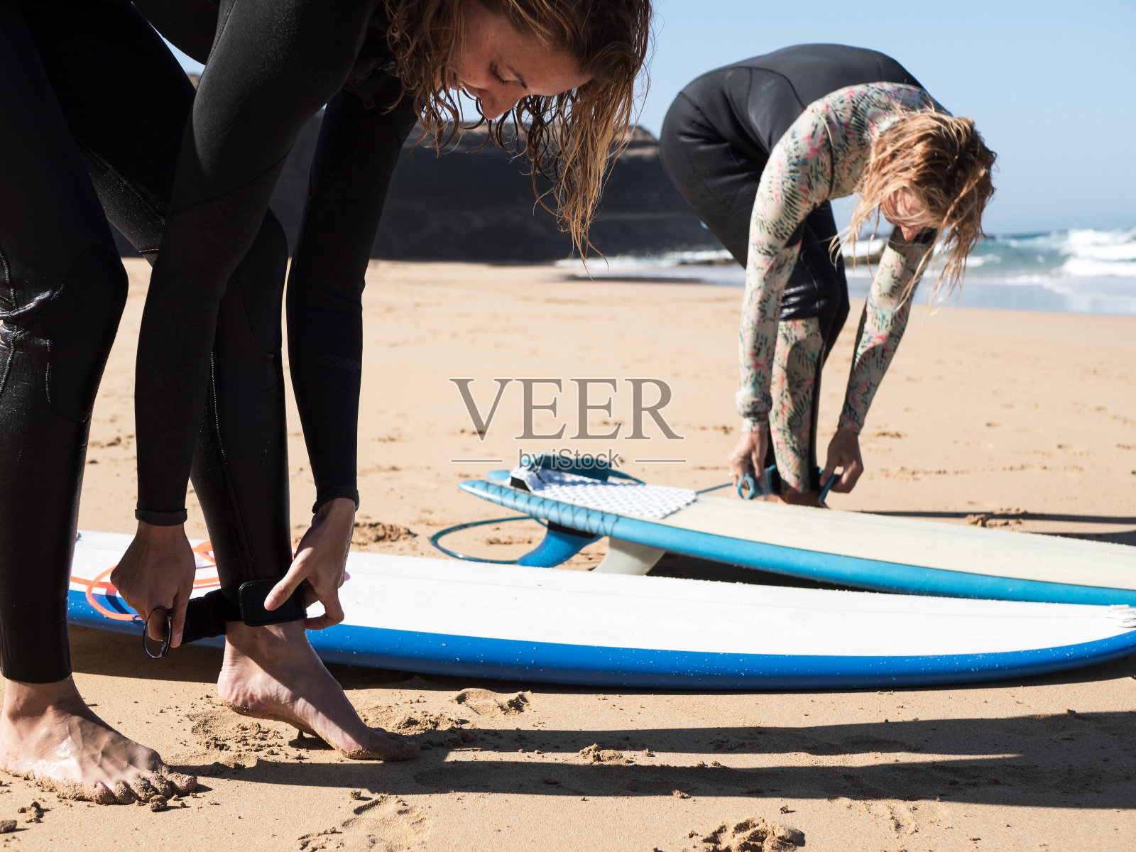 雌性冲浪者将冲浪安全带系在脚踝上照片摄影图片