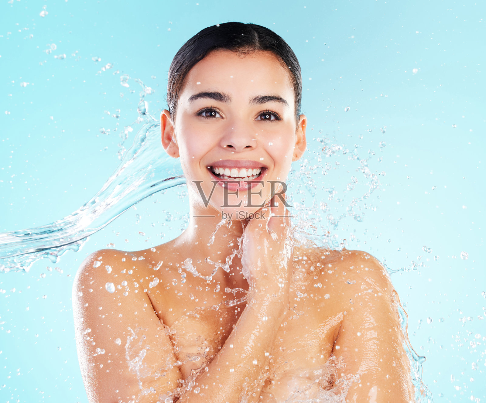 一个美丽的年轻女子被泼在蓝色的背景水照片摄影图片