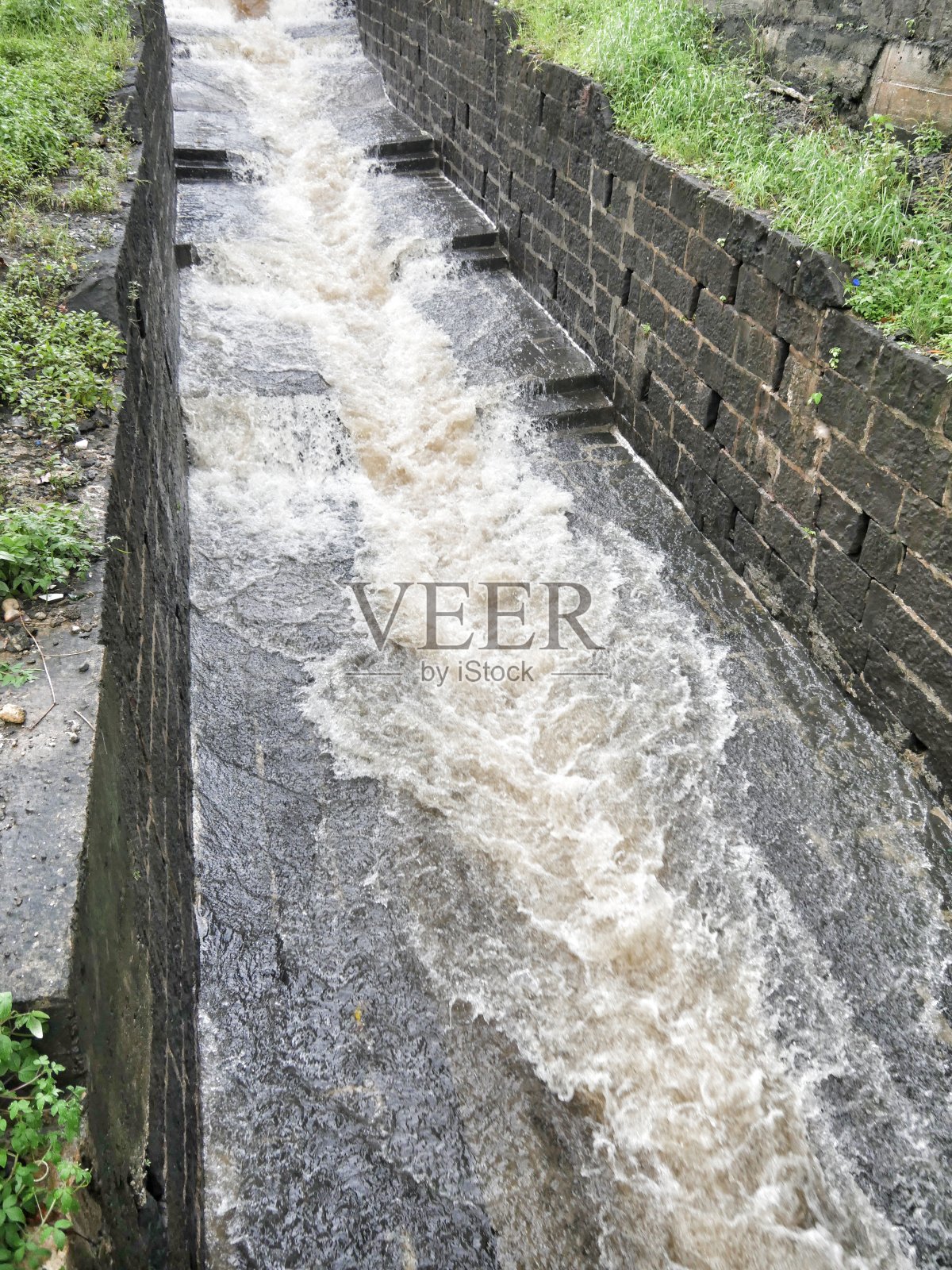 雨水猛烈地涌向铺砌的石头排水沟照片摄影图片