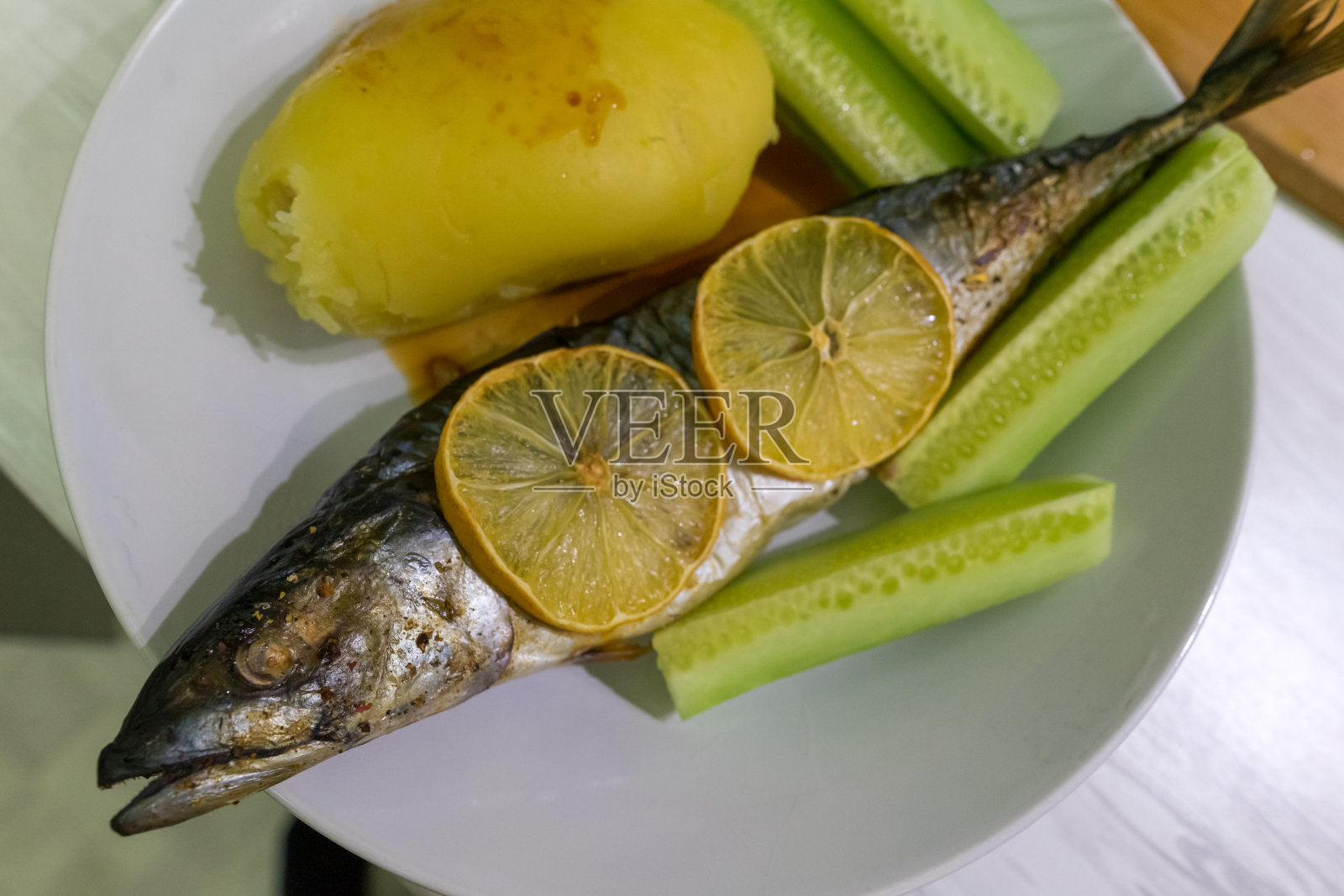 用柠檬、土豆和黄瓜烤制的鱼。照片摄影图片