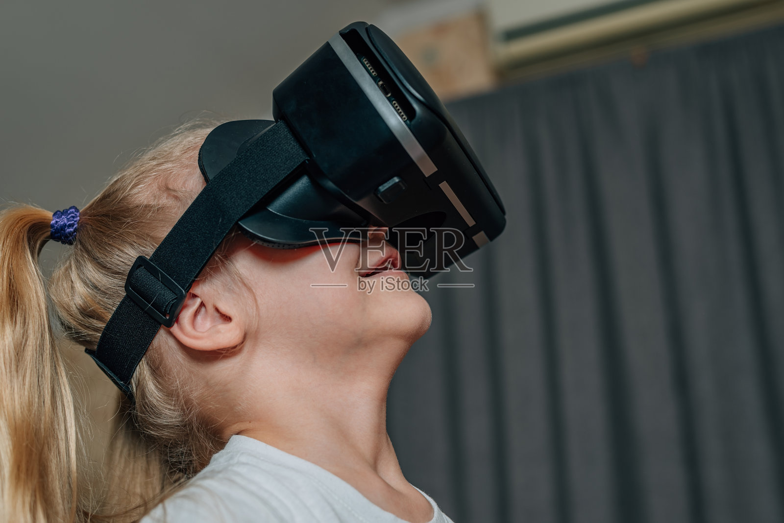 小女孩在家里戴着虚拟现实的VR眼镜看视频,玩游戏。现代的孩子很精通技术革新。一代α照片摄影图片