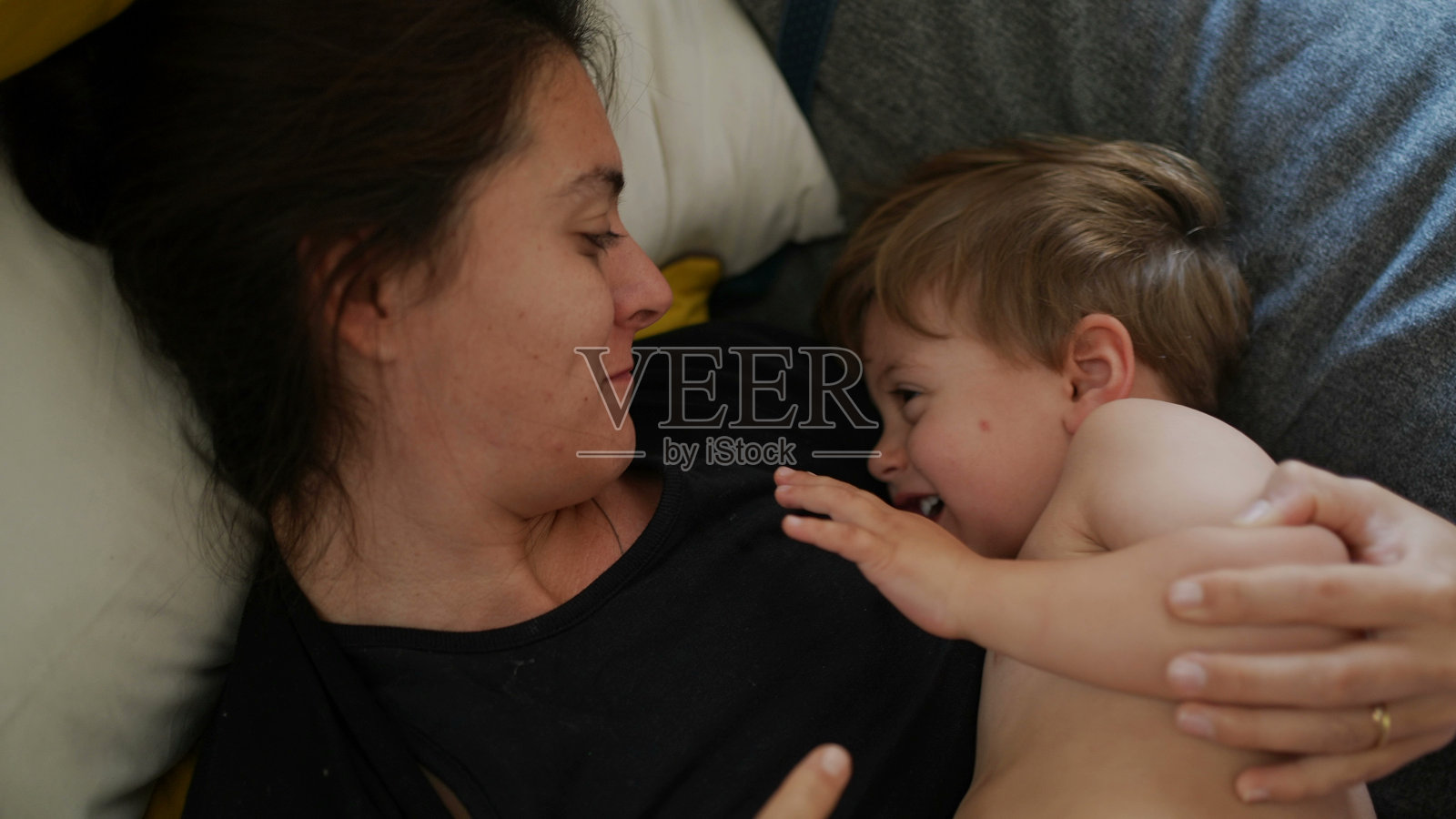 妈妈亲吻幼童的脸颊,调皮的妈妈亲吻孩子照片摄影图片