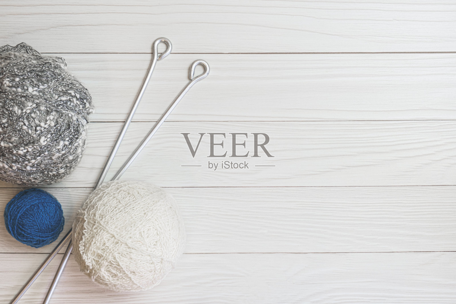 毛线球和长金属针在轻木板的背景上照片摄影图片