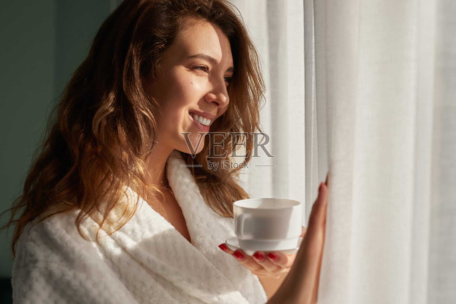 喝着咖啡看着窗户的快乐女人照片摄影图片