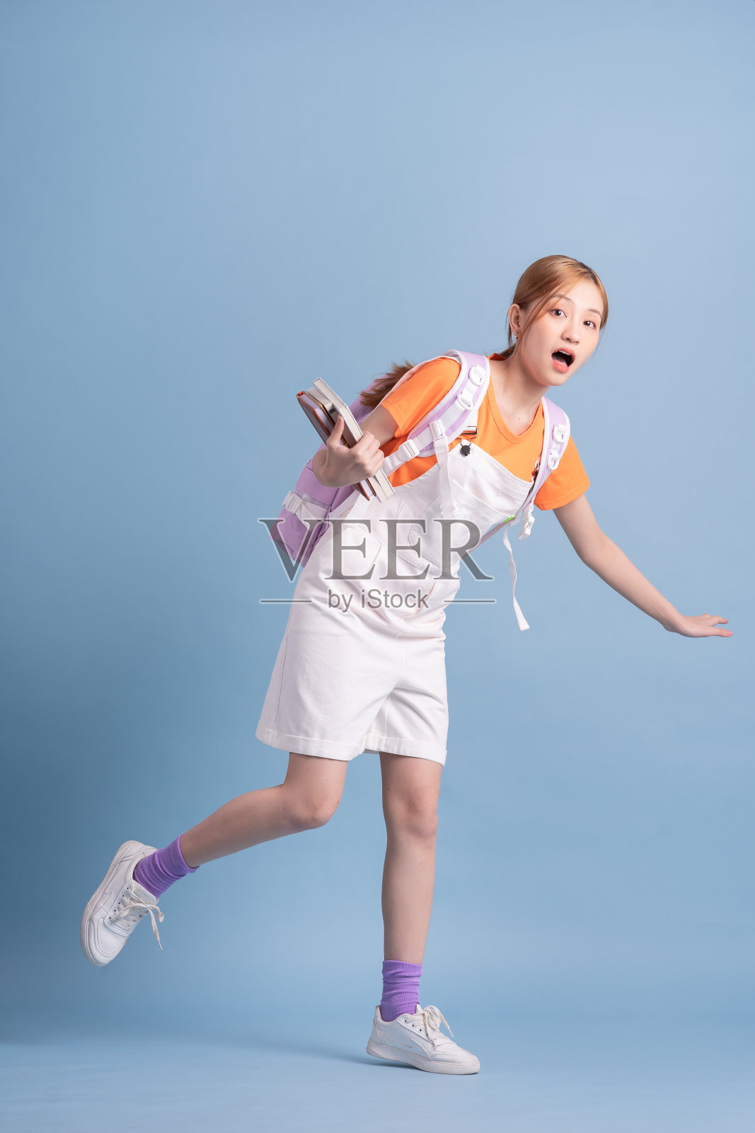 年轻的亚洲学生在蓝色背景上摆姿势照片摄影图片