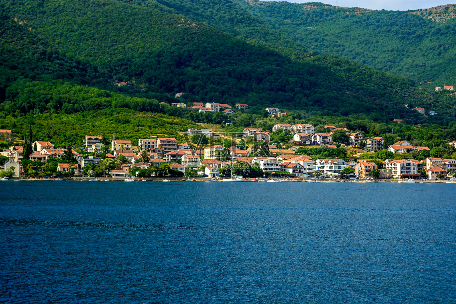 山的背景下,海边的房子照片摄影图片