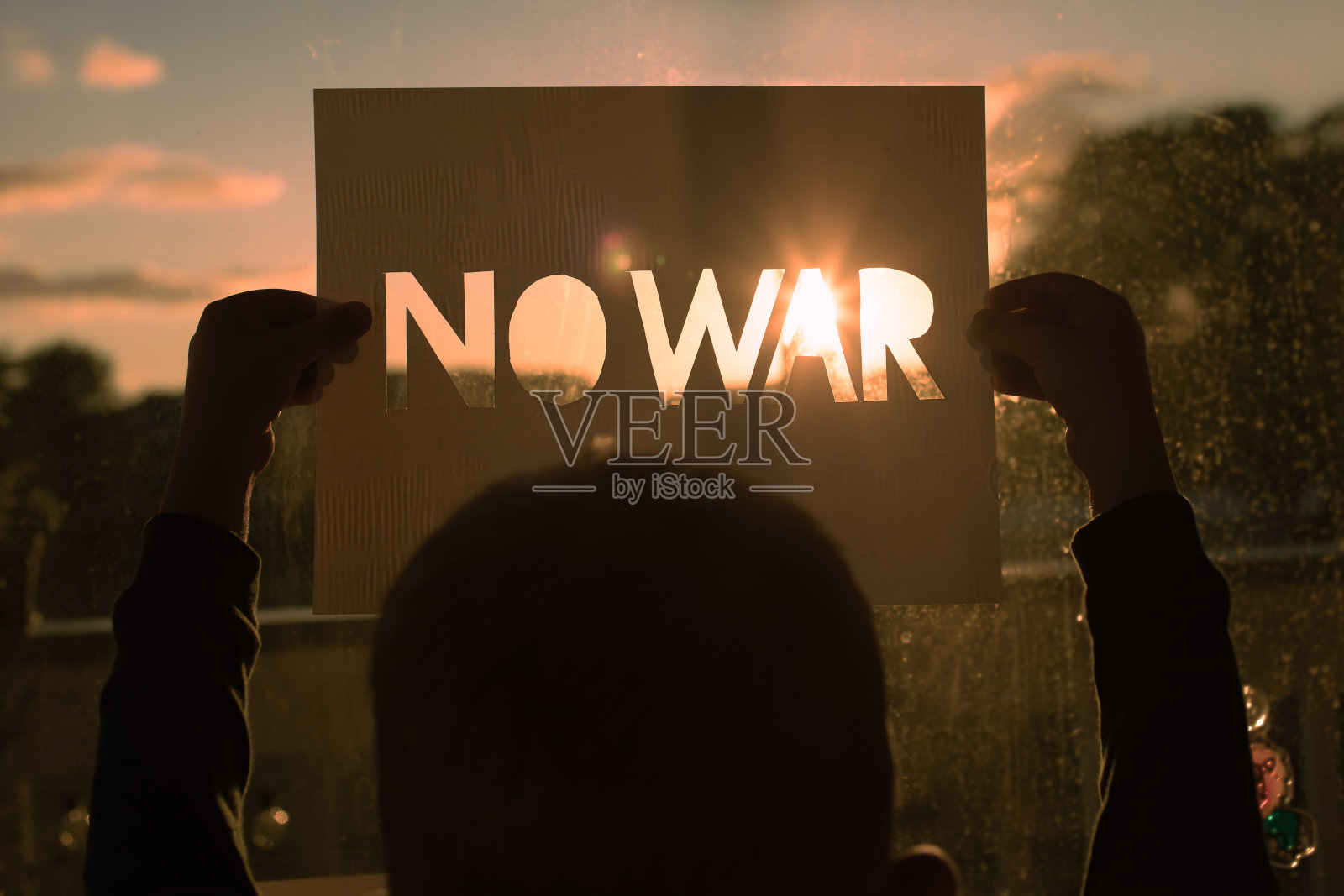 孩子在日落前没有举着战争标志。照片摄影图片