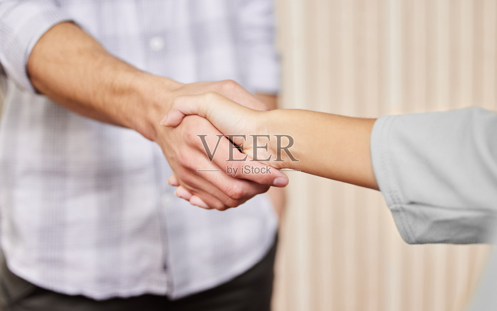 剪裁拍摄的两个不认识的商人握手,而站在一个办公室照片摄影图片