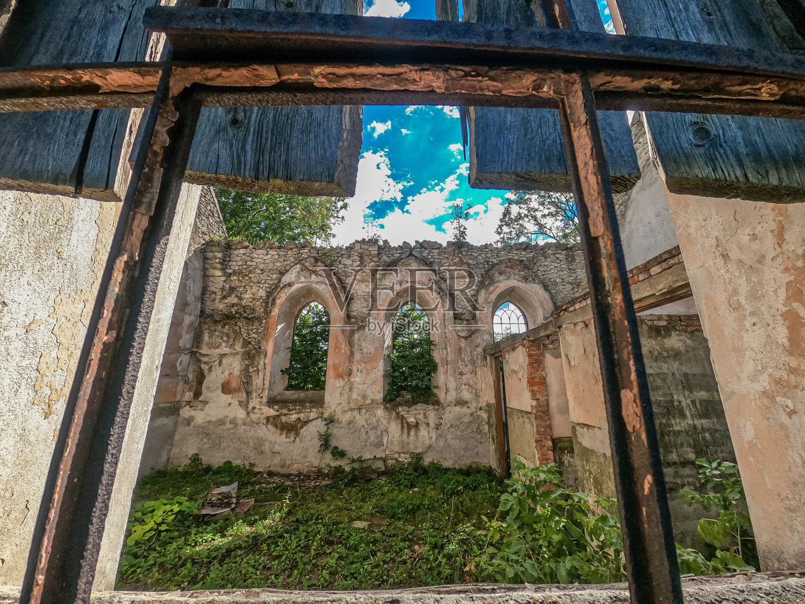 从一座古老的石头教堂破败的窗户可以看到一个空无一人的废弃庭院。拱形窗户,石墙。空的废弃的建筑。照片摄影图片