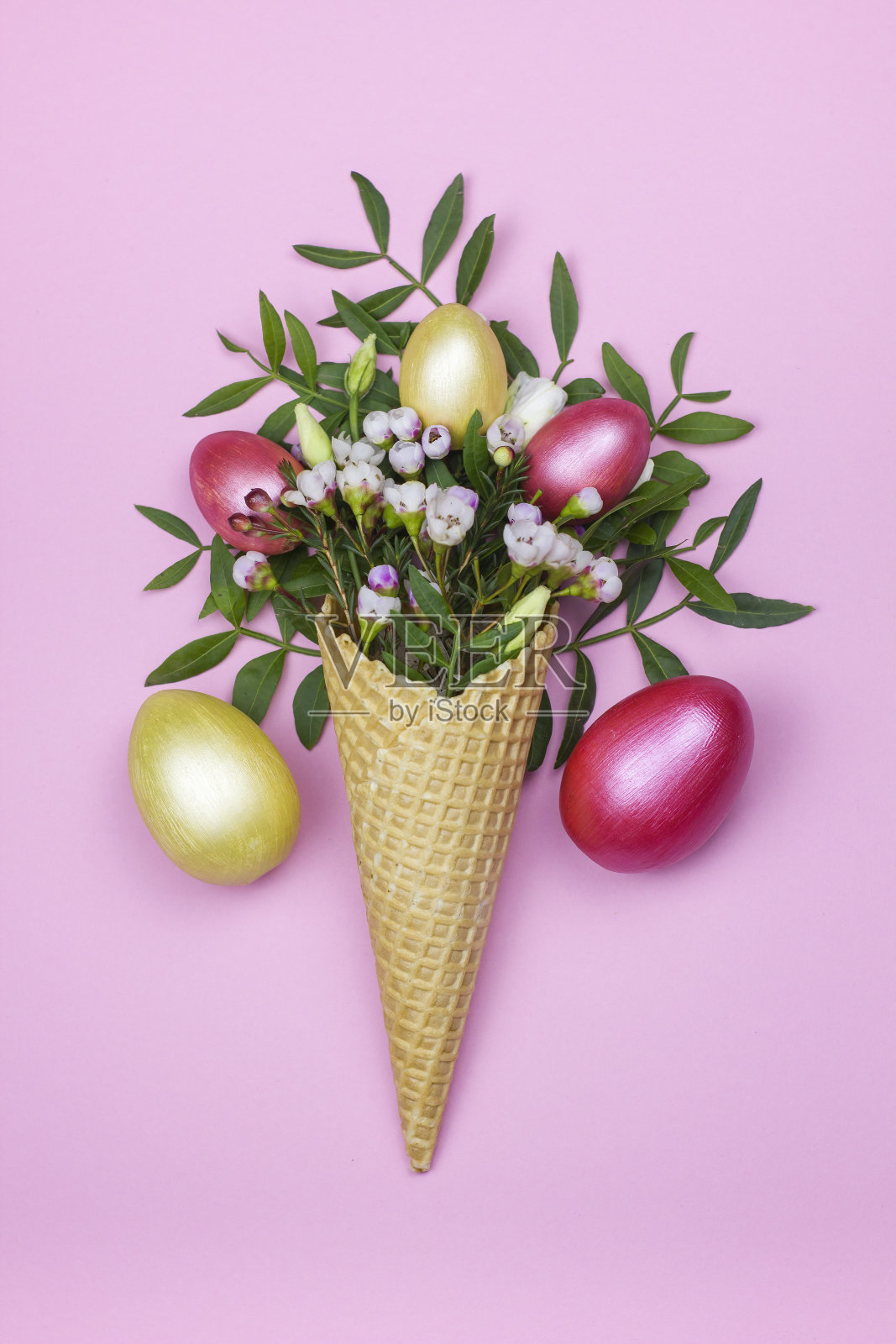华夫饼蛋筒里的复活节彩蛋,粉红色的背景是春天的花朵。照片摄影图片