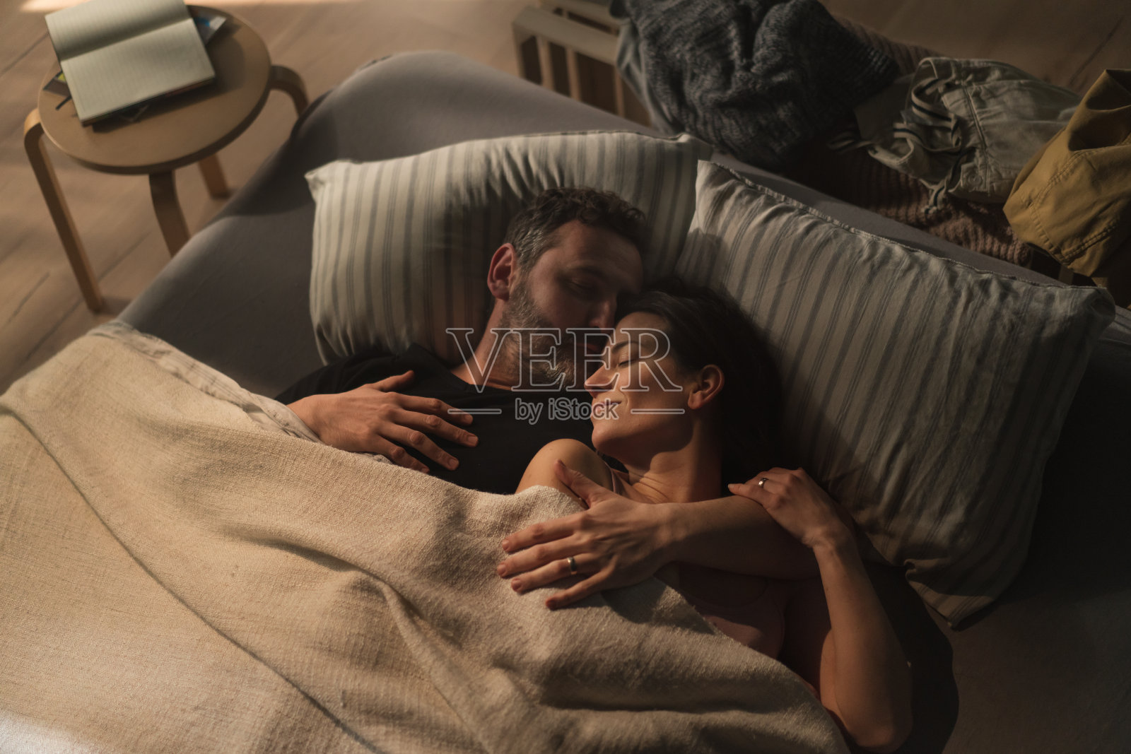 从头顶上看,这对中年夫妇晚上躺在床上,拥抱着,看着对方。照片摄影图片