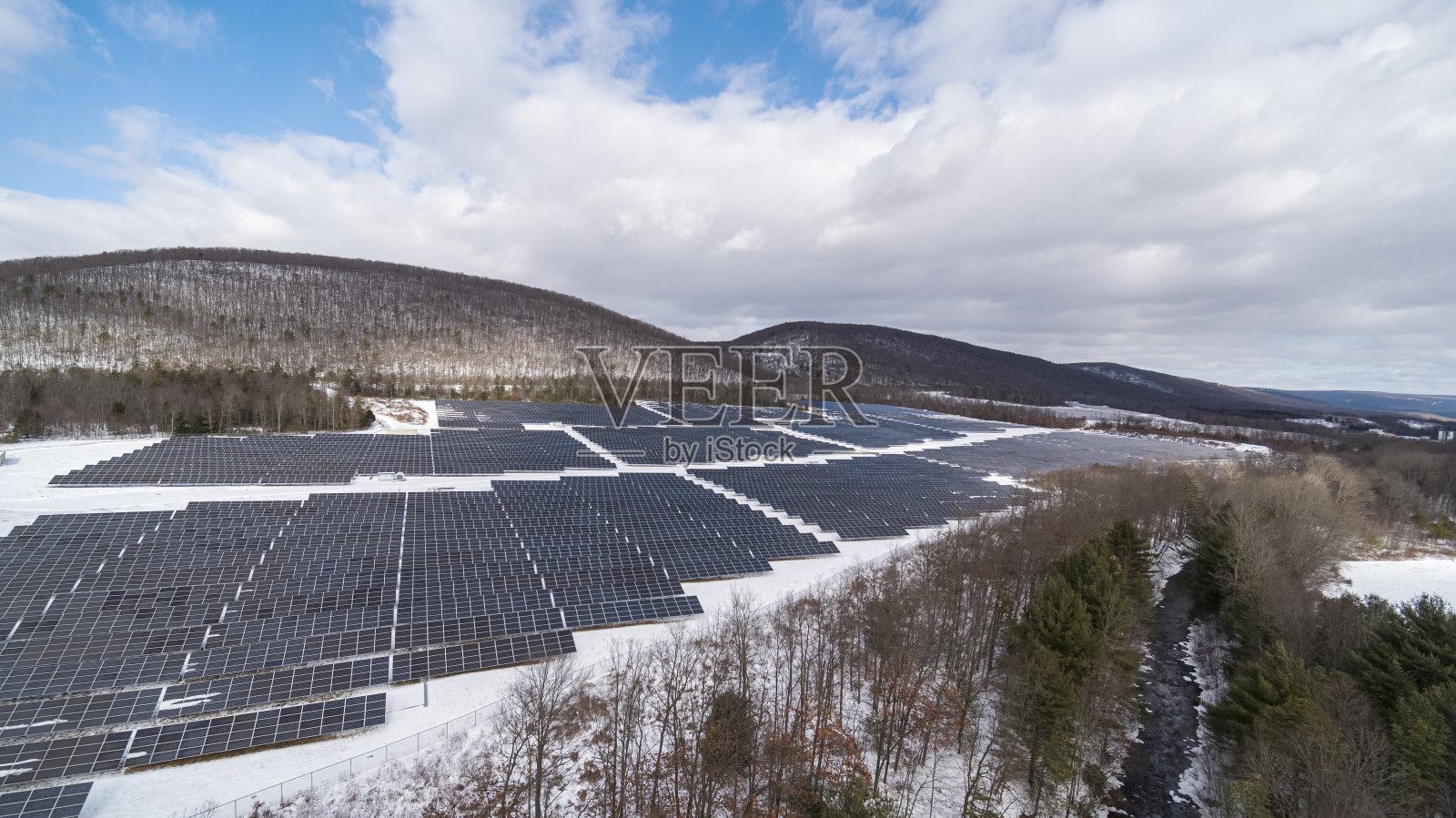 宾夕法尼亚州阿巴拉契亚山脉的大型太阳能农场,在一个阳光明媚的冬日里,一场大雪过后。照片摄影图片