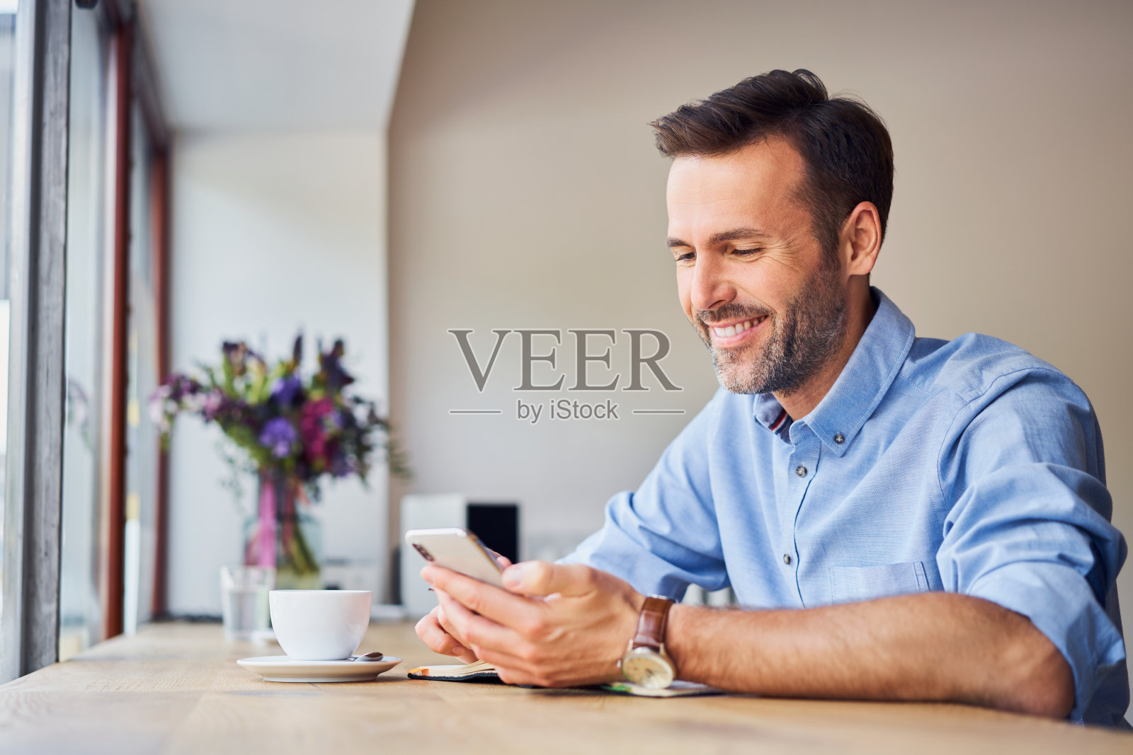 快乐的商人在工作休息时在咖啡店里看着他的智能手机照片摄影图片
