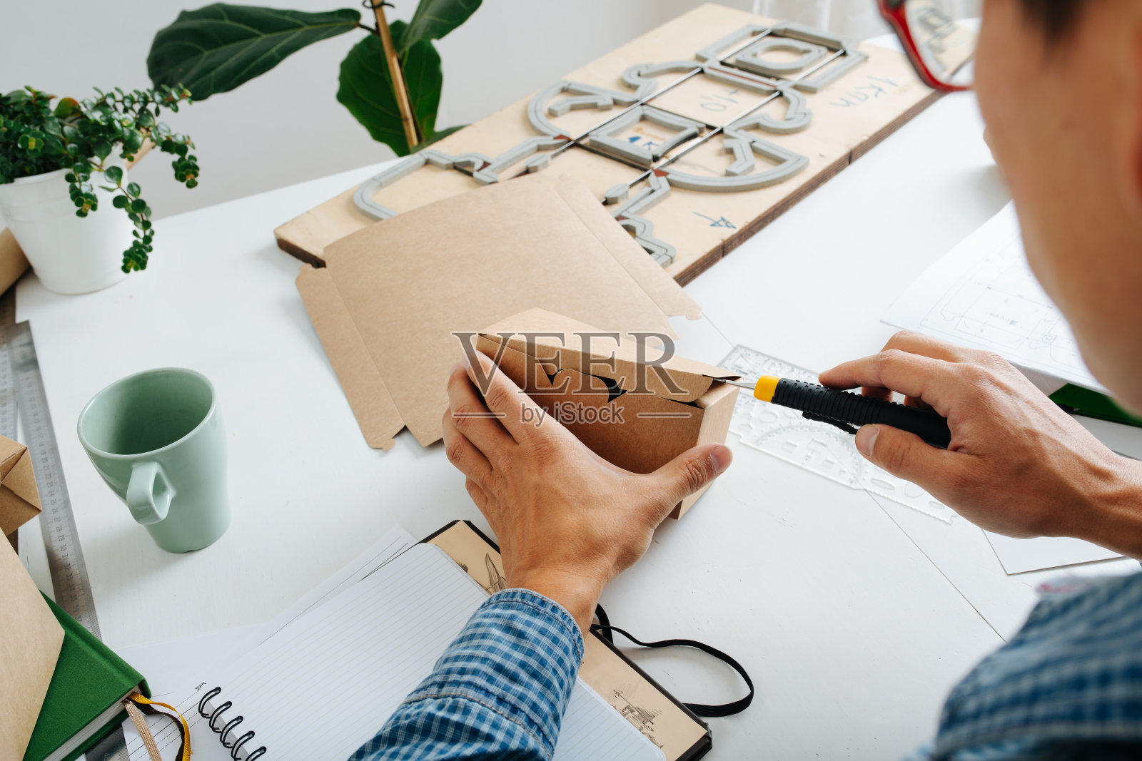 努力工作的设计师用裁纸刀检查盒子原型照片摄影图片