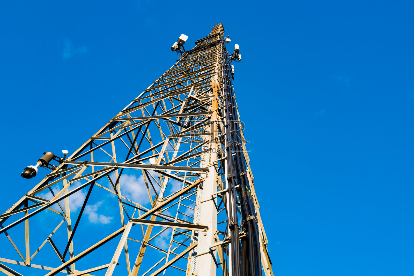 通信塔的垂直视图,显示已安装的多业务电信设备,包括微波和5G蜂窝中继器。照片摄影图片